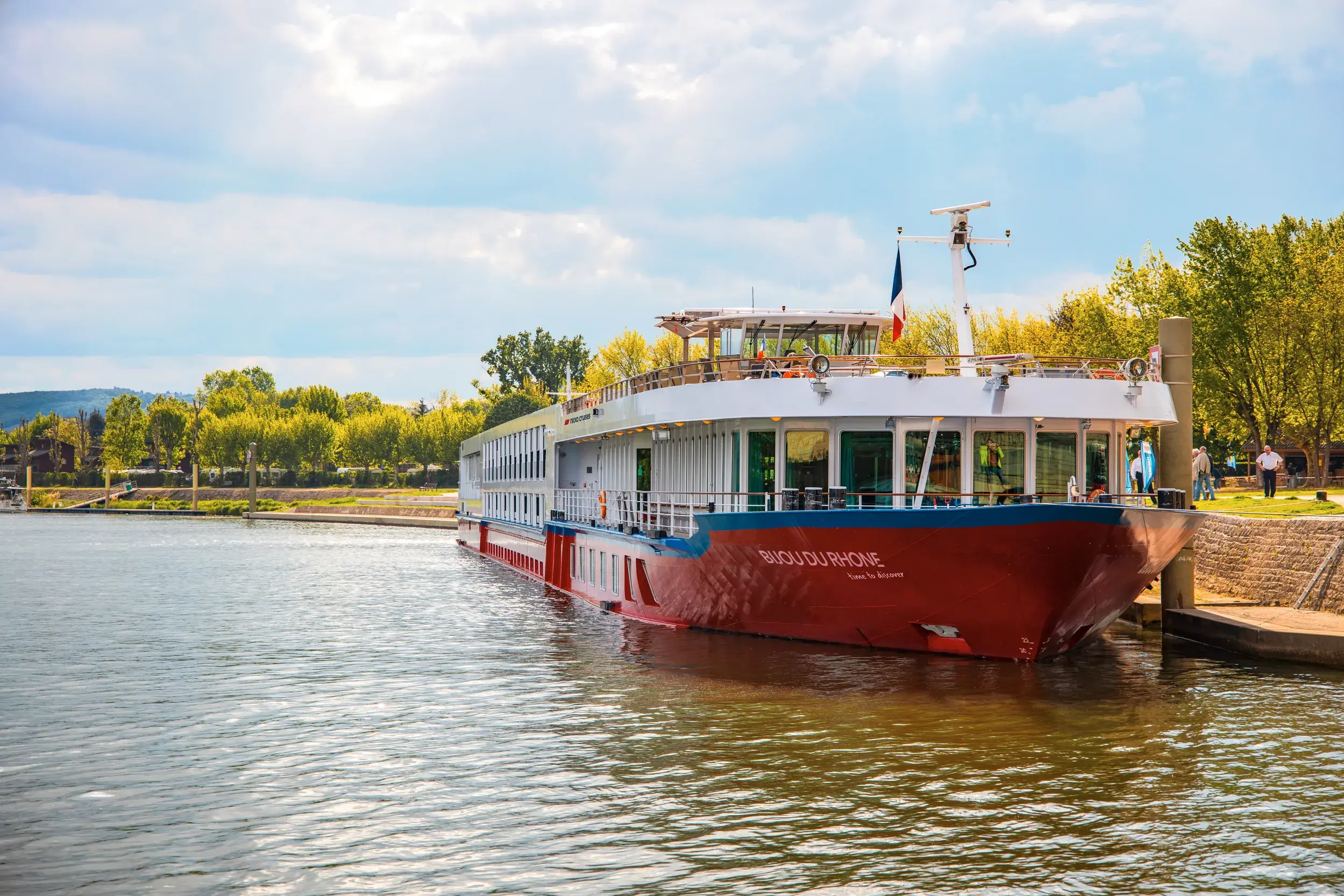 Flusskreuzfahrtschiff Bijou du Rhône liegt an der Anlegestelle an der Rhone vor baumbestandener Kulisse
