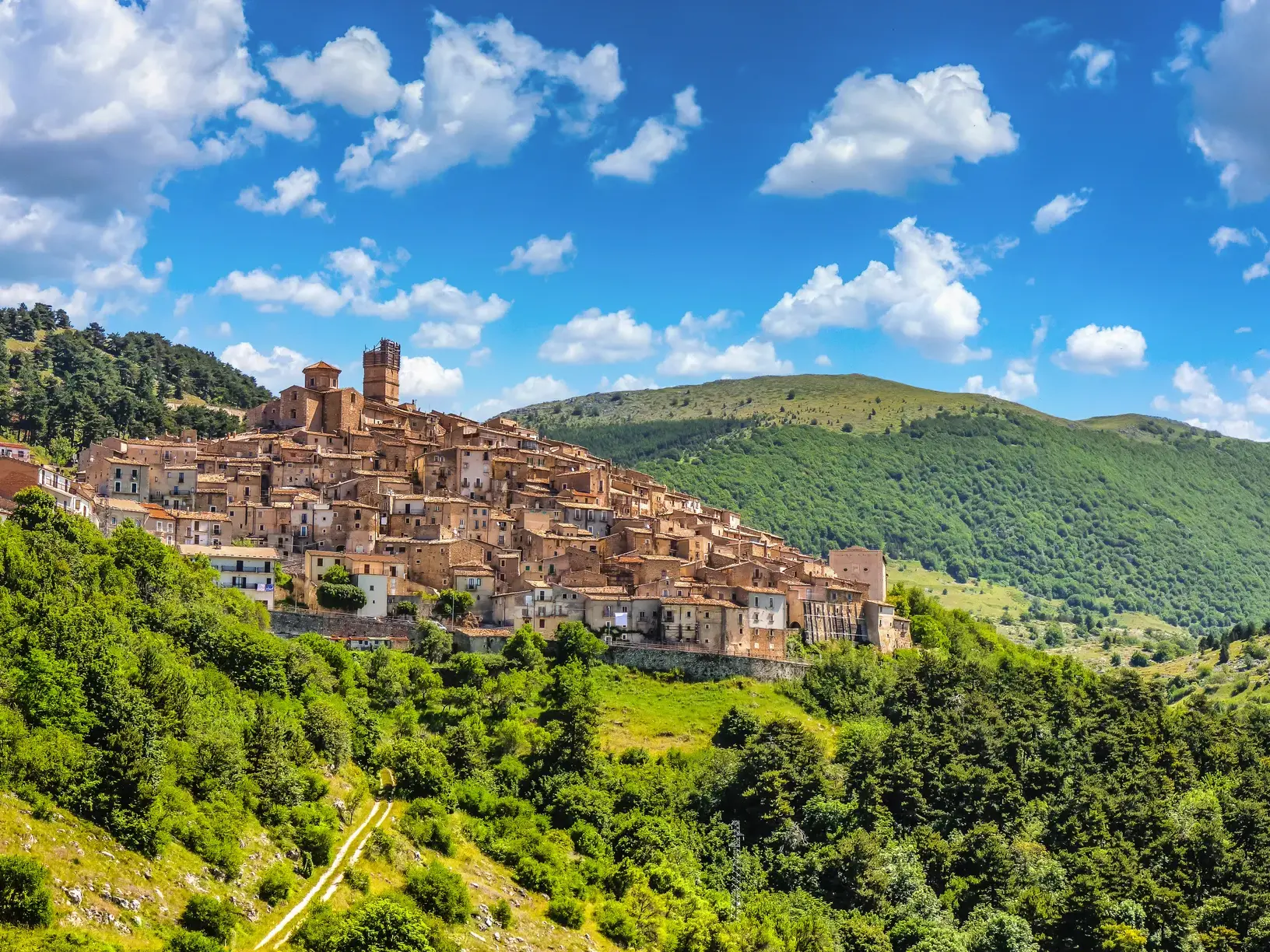 Malerisches Bergdorf Santo Stefano di Sessanio in den Abruzzen, eingebettet in die grüne Hügellandschaft des Nationalparks Gran Sasso.