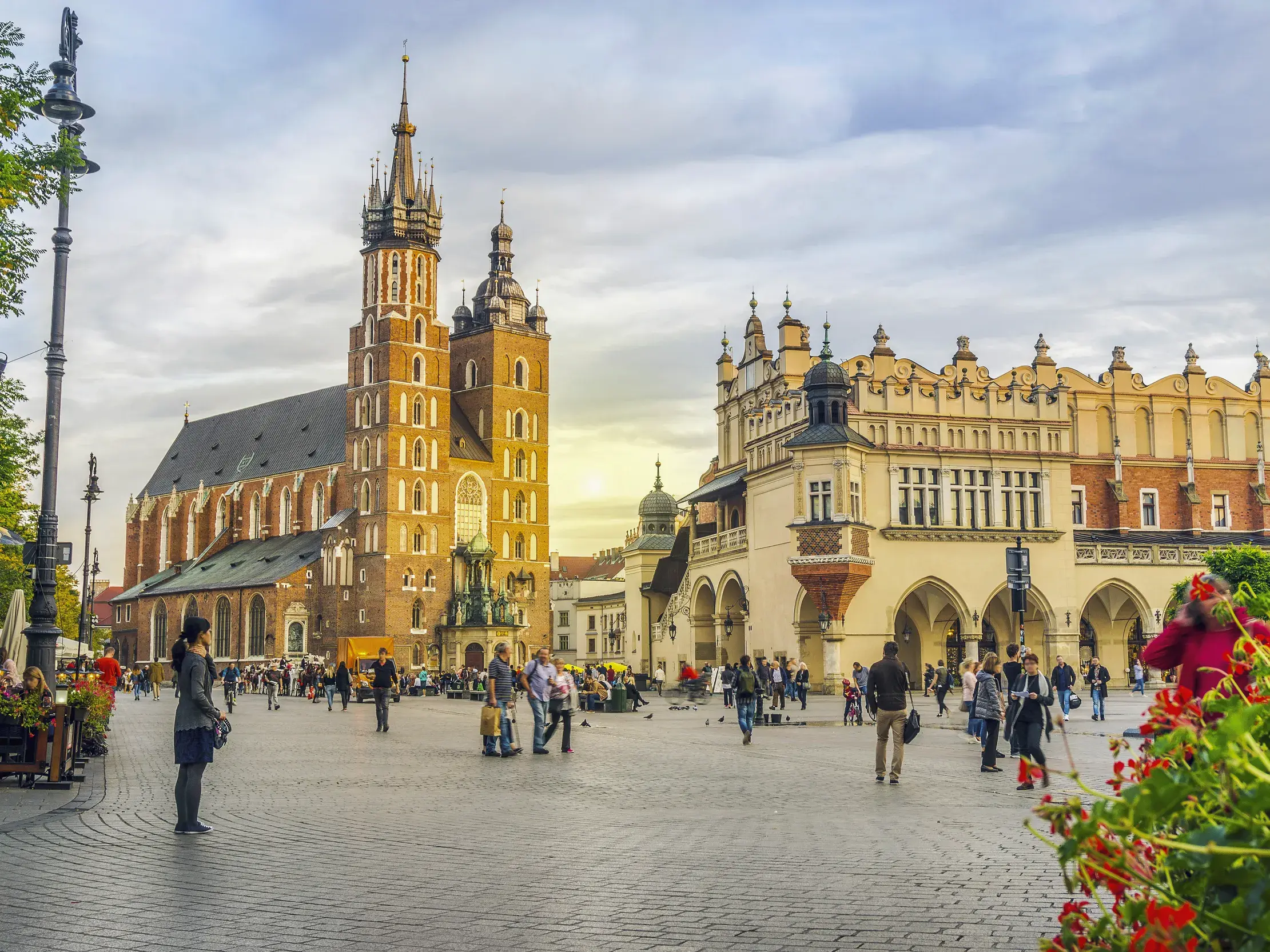 Historischer Marktplatz in Krakau mit der gotischen Marienkirche und den Tuchhallen bei Dämmerung.