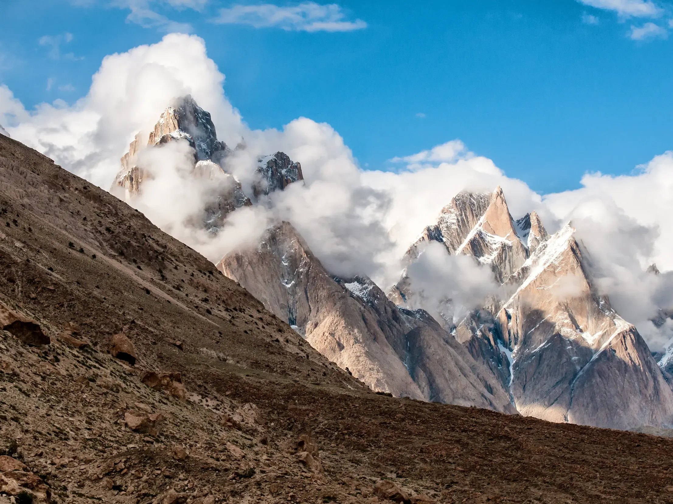Majestätische Gipfel der Trango-Gruppe im Karakorum, von Wolken umspielt, während des Trekkings auf dem Baltoro-Gletscher.