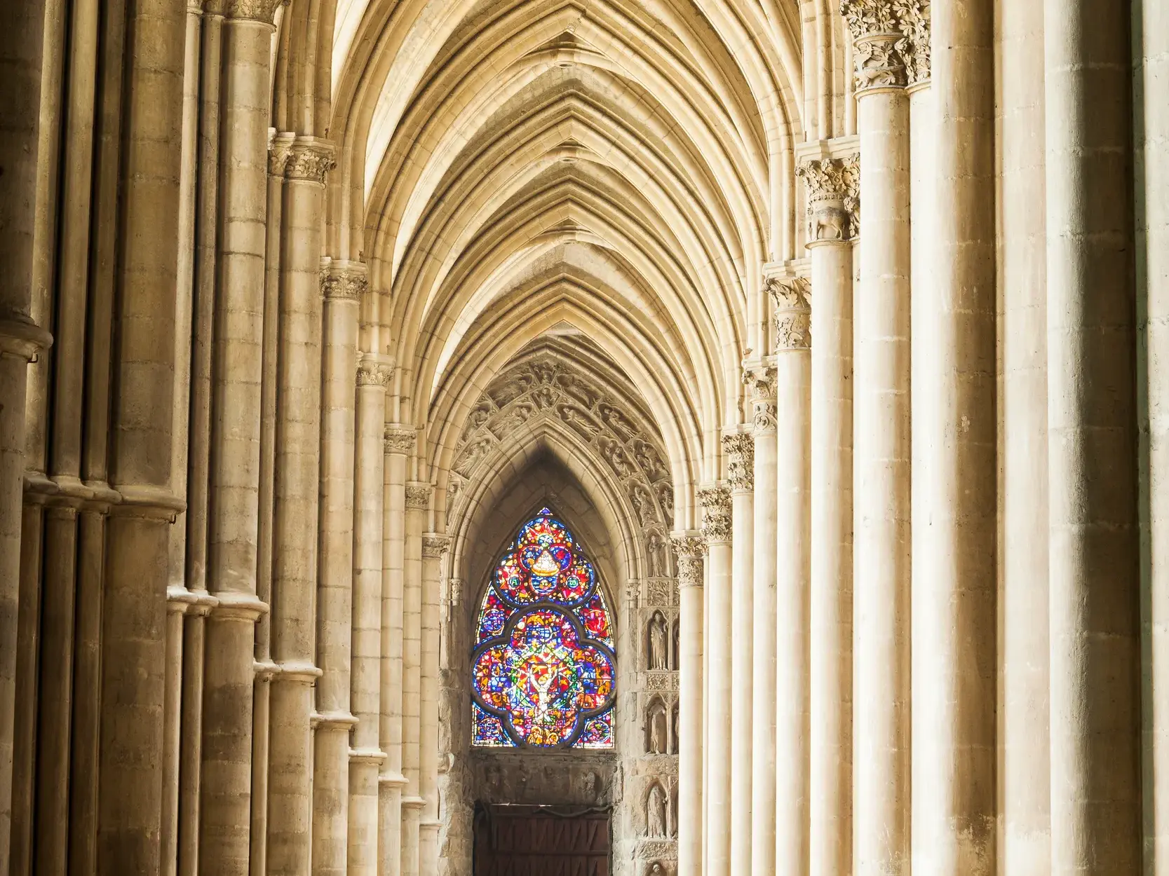 Majestätische Steinsäulen und gotische Bögen führen den Blick zum leuchtenden Buntglasfenster der Kathedrale von Chartres.