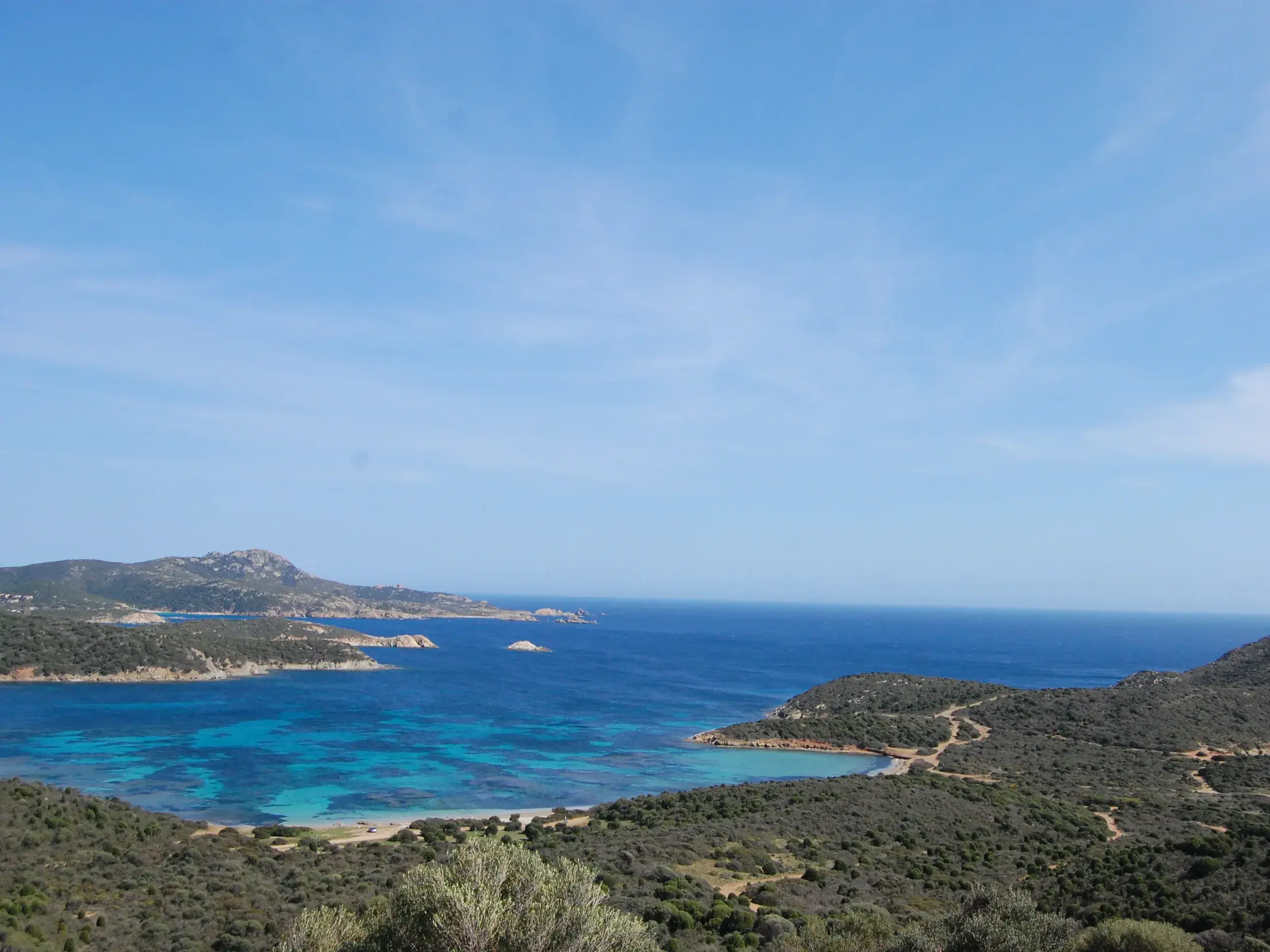 Malerische Küste Südsardiniens mit türkisblauem Meer, einer sandigen Bucht, grüner Macchia und einem alten Sarazenenturm.