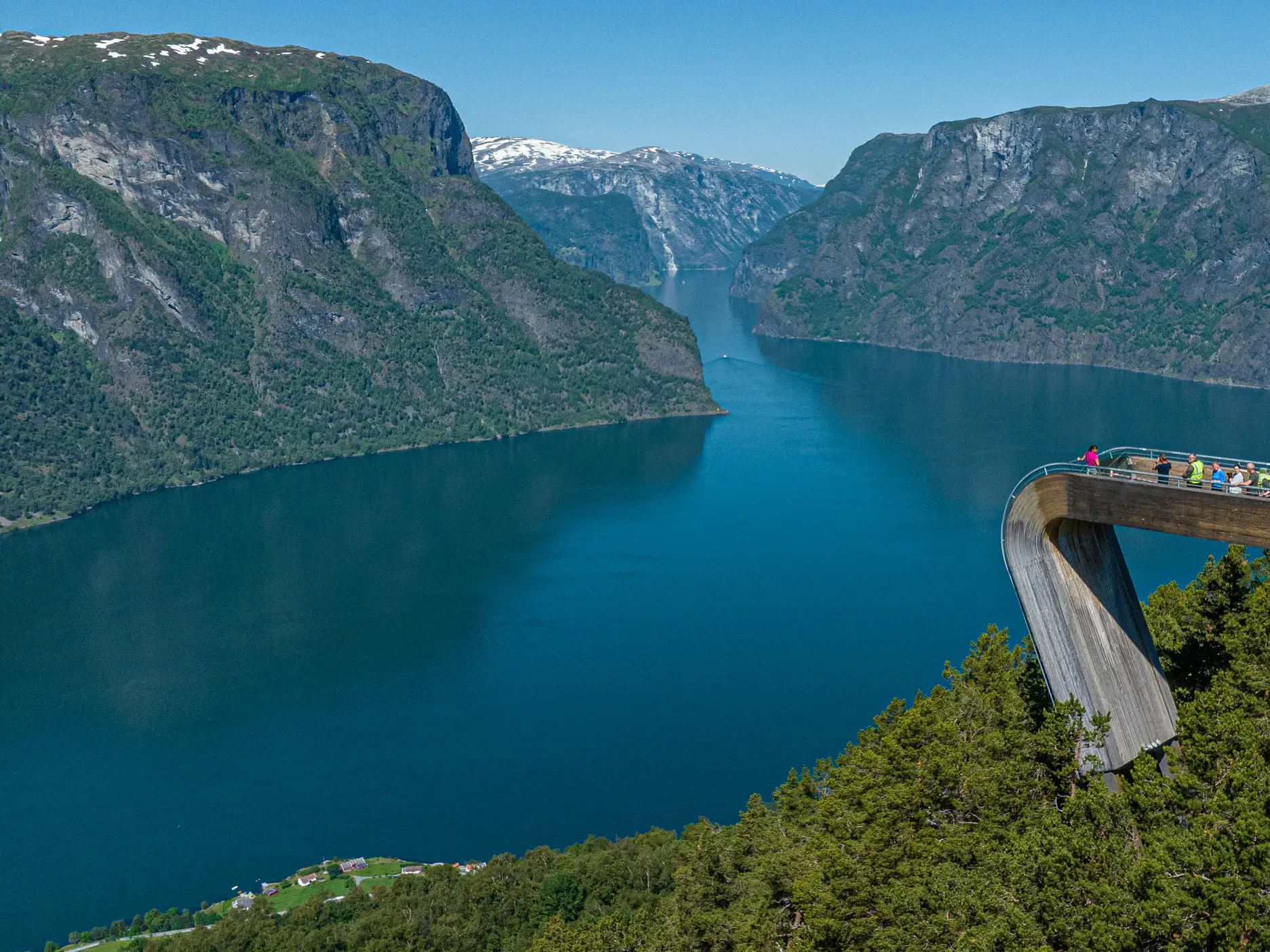 Reisende auf der Aussichtsplattform Stegastein genießen den weiten Blick über den tiefblauen Aurlandsfjord in Norwegen.