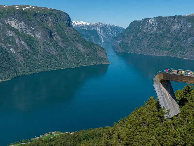 Reisende auf der Aussichtsplattform Stegastein genießen den weiten Blick über den tiefblauen Aurlandsfjord in Norwegen.