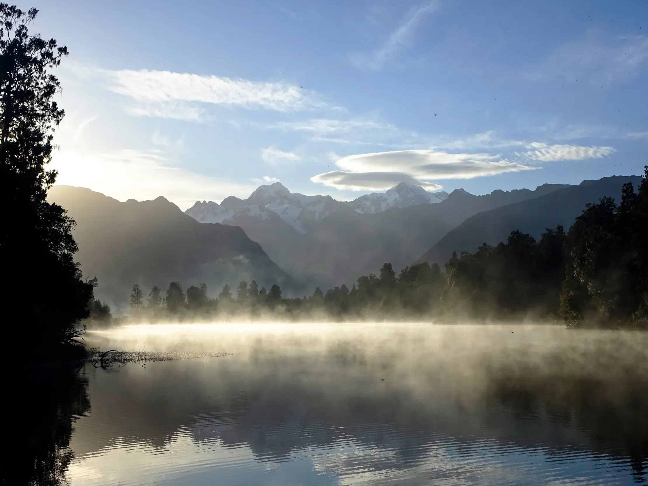 Auf einer Wanderreise in Neuseeland den Sonnenaufgang an einem nebligen See vor den majestätischen Südalpen erleben.