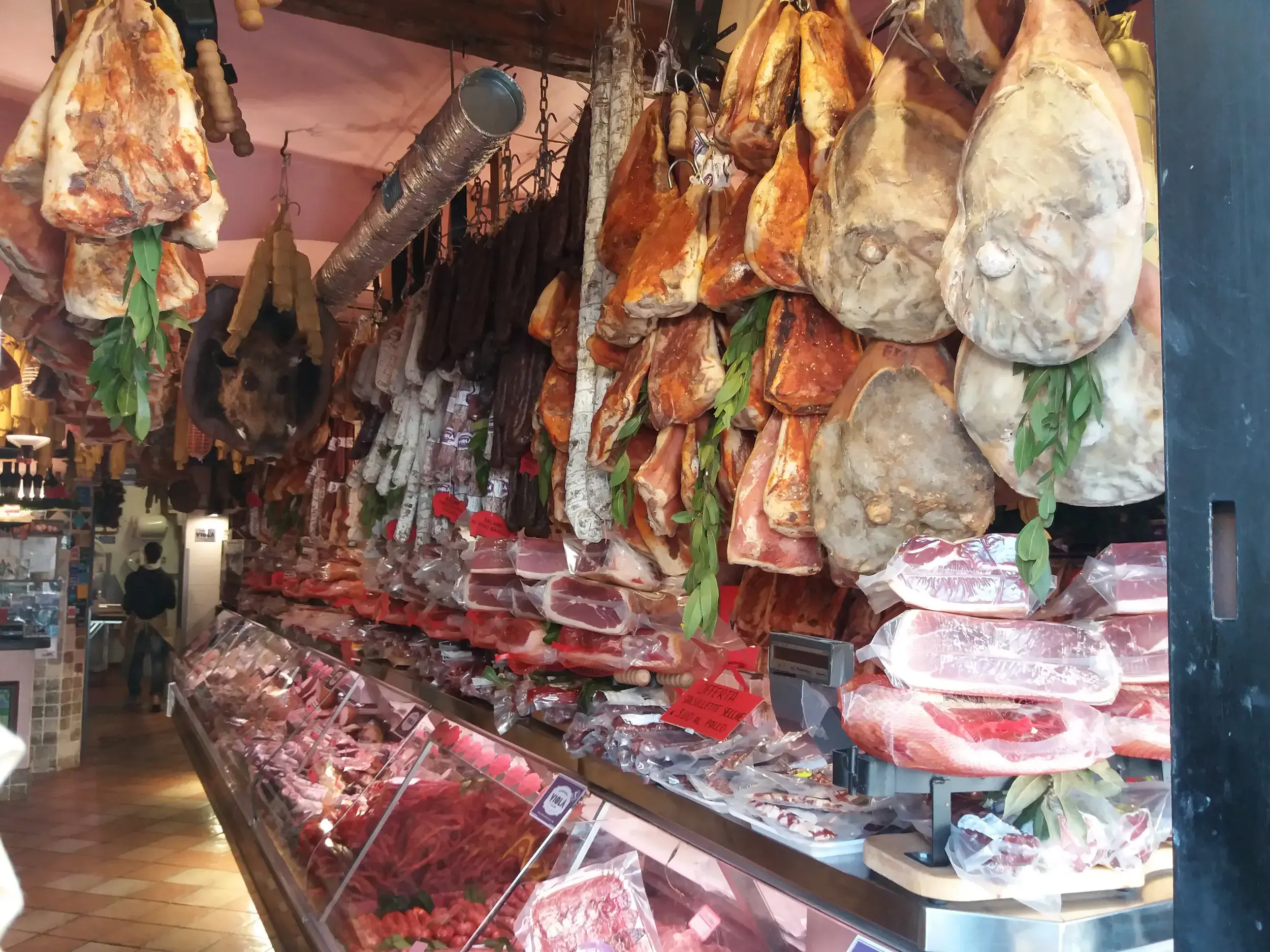Kulinarische Entdeckung in der Toskana: Von der Decke hängende Schinken und Salamis in einer traditionellen Metzgerei.
