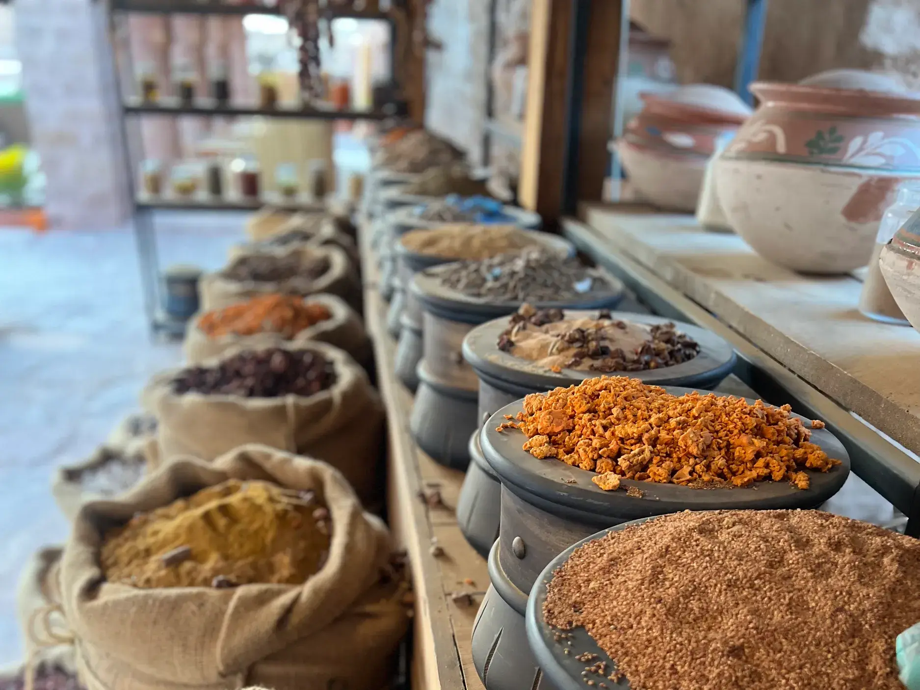 Eine Auswahl bunter, orientalischer Gewürze in traditionellen Töpfen und Säcken auf einem Markt in der Altstadt von Al Ula.