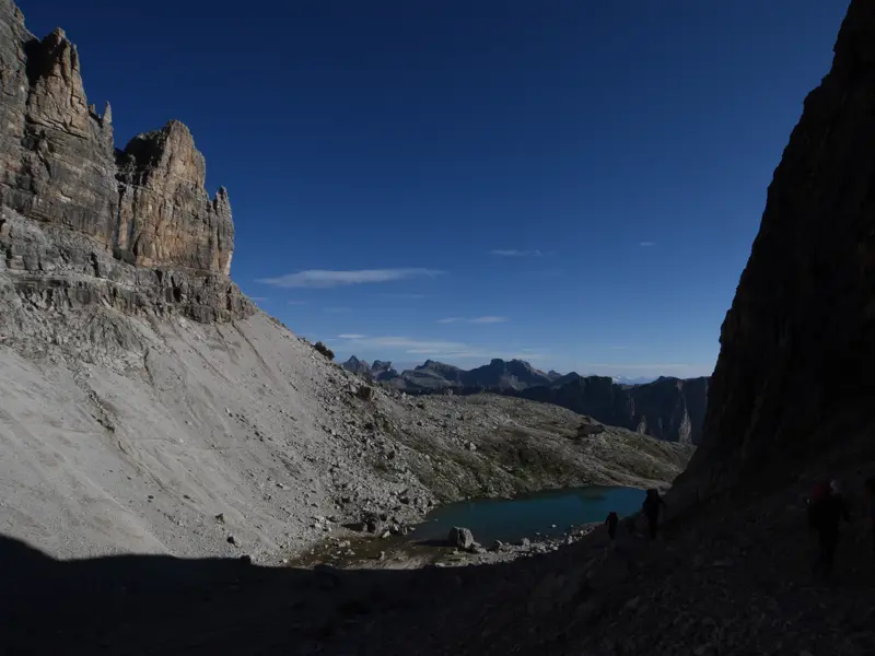 Eine Hauser-Wandergruppe steigt auf einem schattigen Pfad zum türkisfarbenen Lago de Pisciadù in der Sella-Gruppe ab.