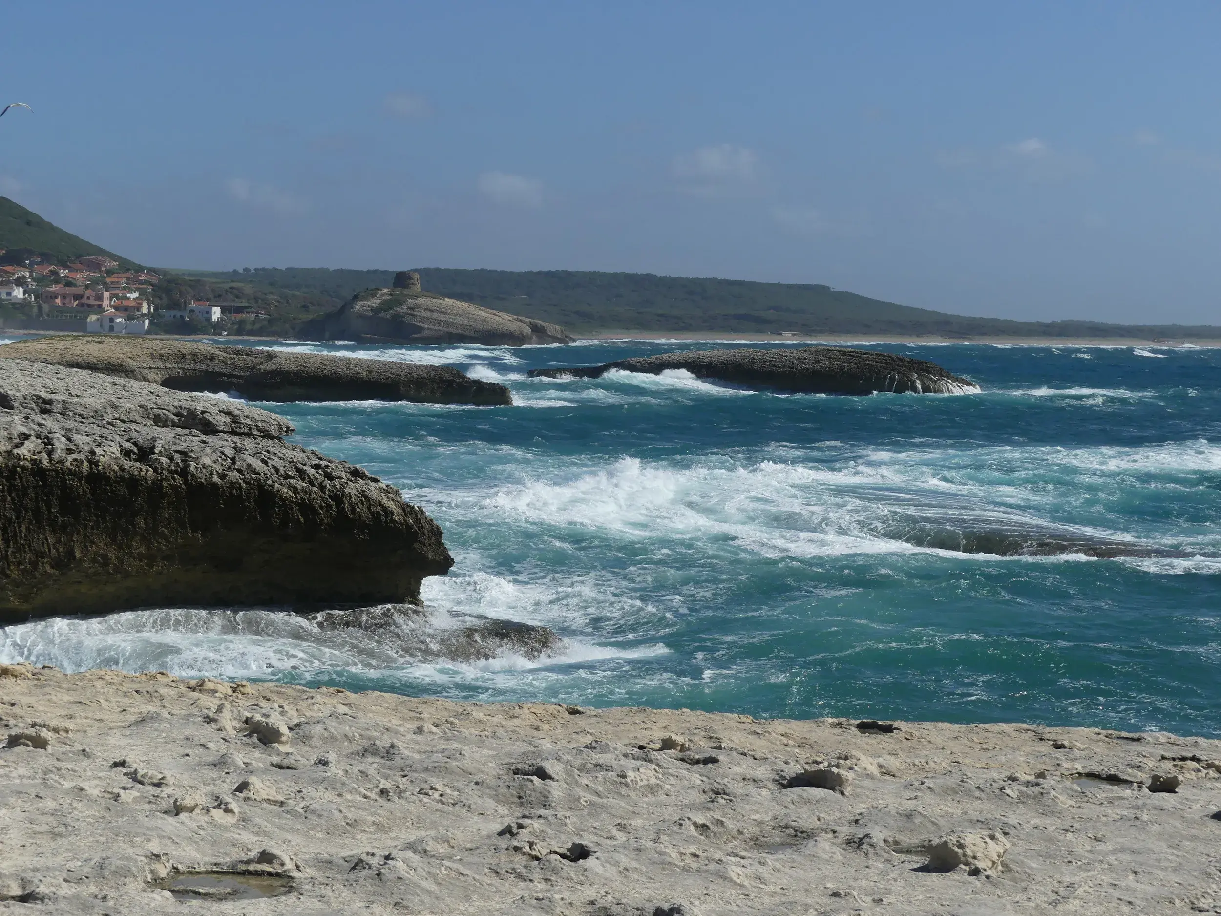 Raue Brandung am Küstenwanderweg der Halbinsel Sinis mit Blick auf die zerklüftete Westküste Sardiniens.