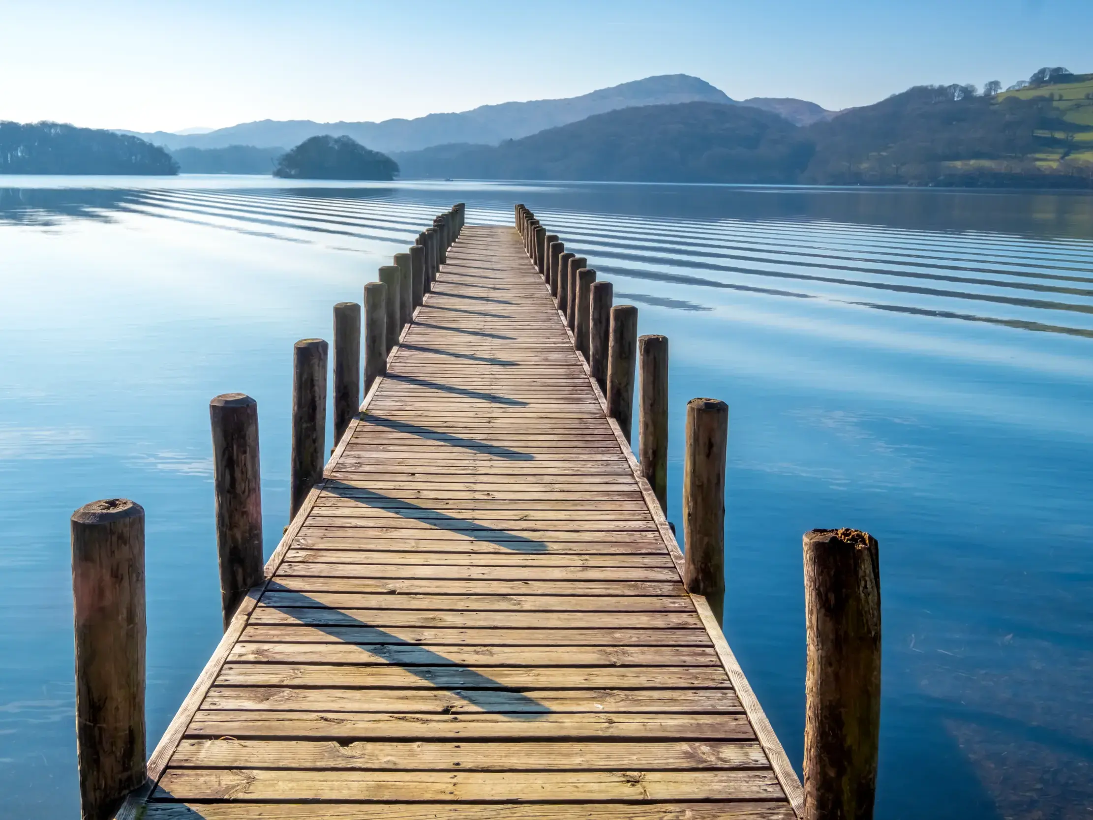 Langer Holzsteg auf dem blauen Ullswater See im UNESCO-Welterbe Lake District unter klarem Himmel.