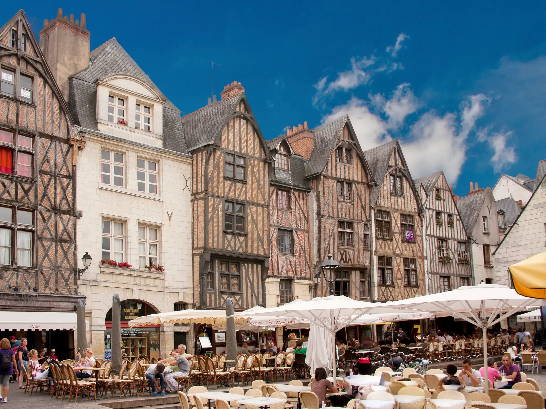 Historische Fachwerkhäuser am belebten Place Plumereau in Tours, wo Besucher in zahlreichen Straßencafés das französische Flair genießen.