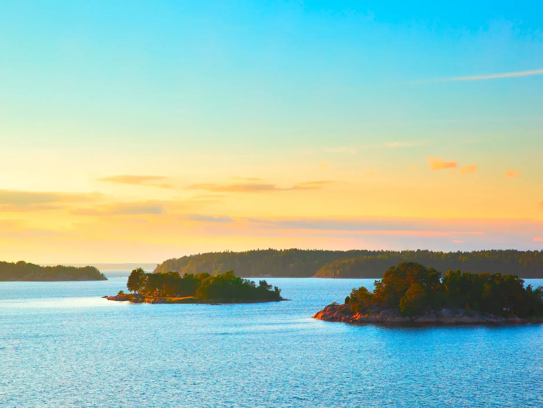 Goldener Sonnenuntergang über den felsigen, bewaldeten Inseln des Finnischen Schärengartens vor der Küste von Turku.