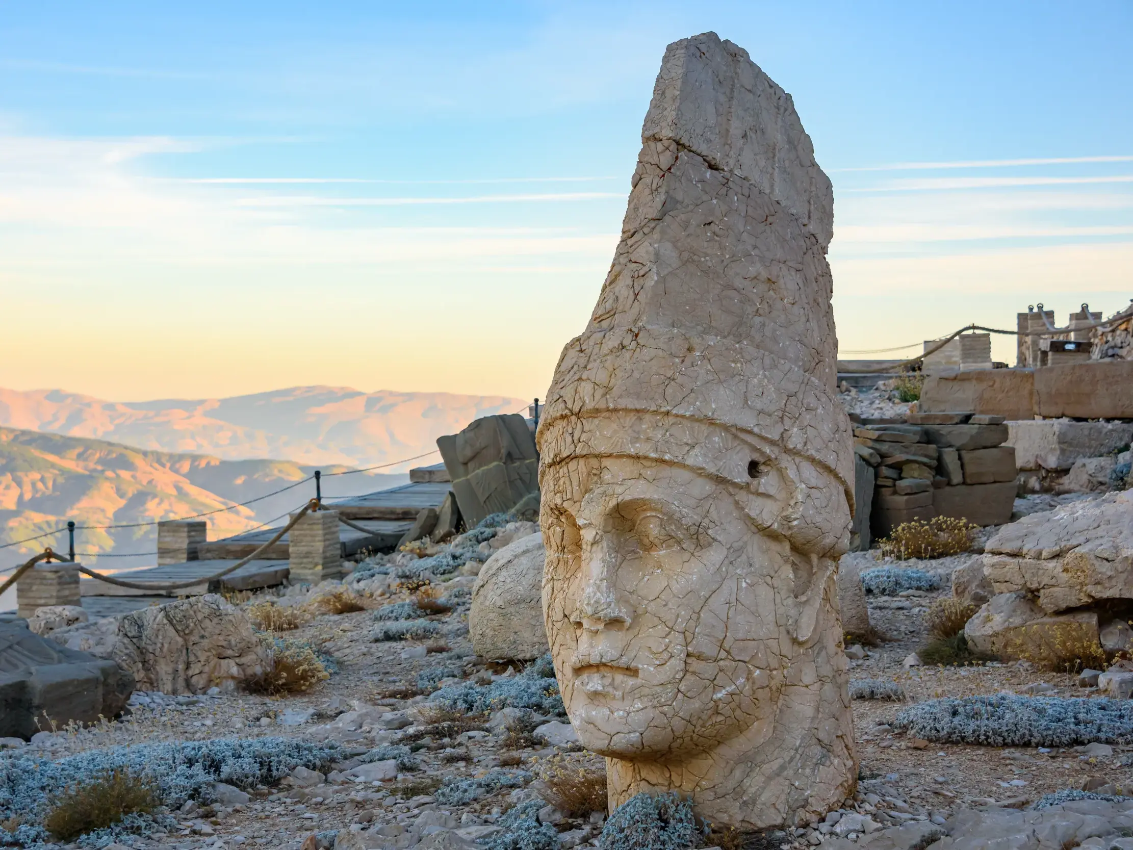 Verwitterter, monumentaler Steinkopf von Antiochos I. auf dem Gipfel des Nemrut Dag mit Blick auf die weite Berglandschaft.