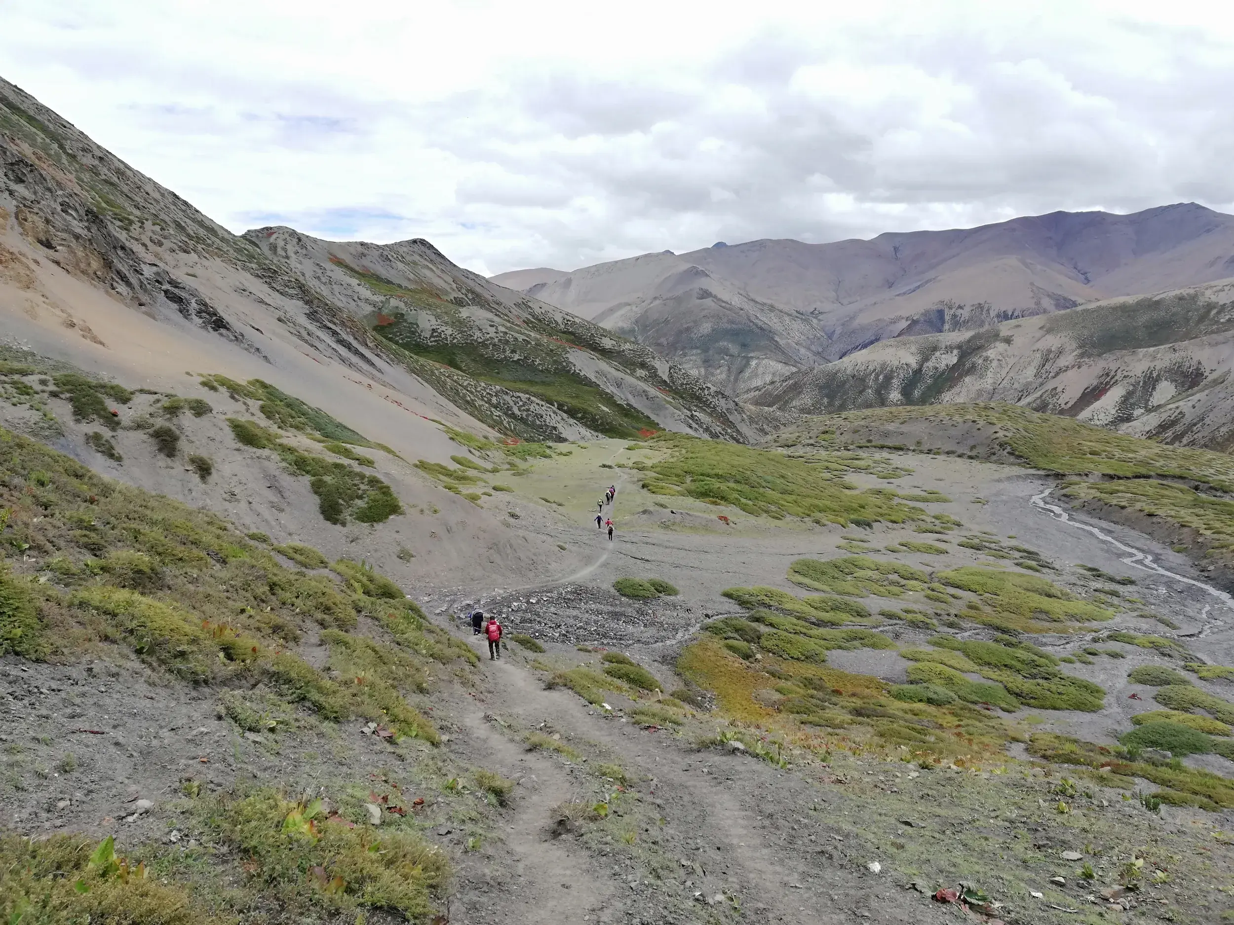 Eine Trekkinggruppe auf einem schmalen Pfad entlang eines Berghangs im weiten, abgelegenen Tal der Dolpo-Region in Nepal.
