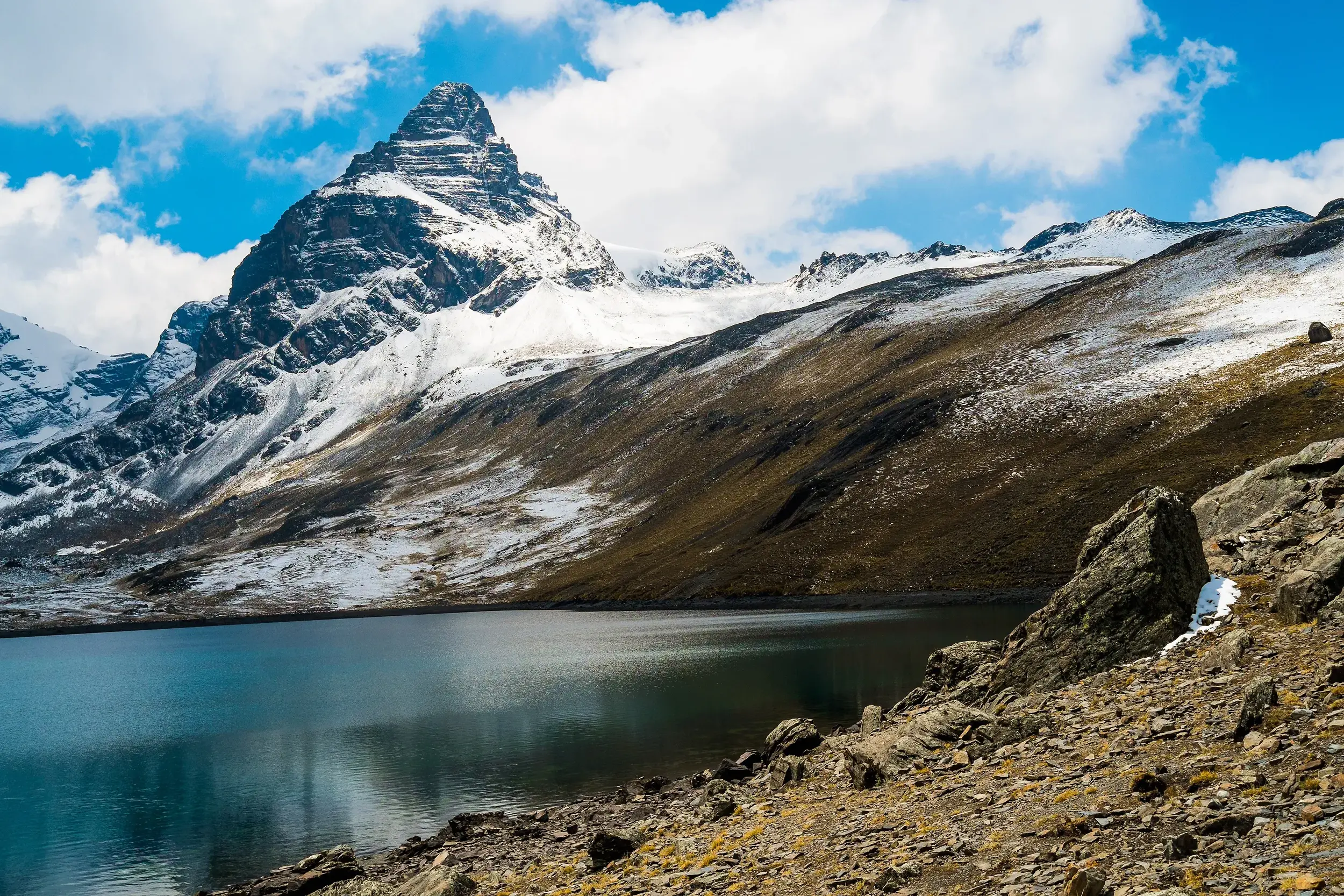 Majestätischer Blick auf den pyramidenförmigen Alpamayo und einen tiefblauen See während des Trekkings in der Cordillera Blanca.
