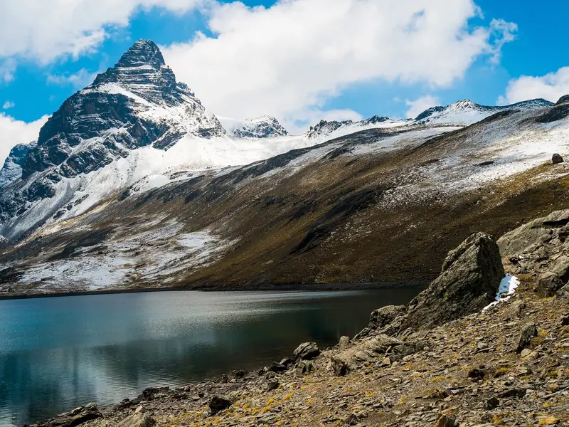 Majestätischer Blick auf den pyramidenförmigen Alpamayo und einen tiefblauen See während des Trekkings in der Cordillera Blanca.