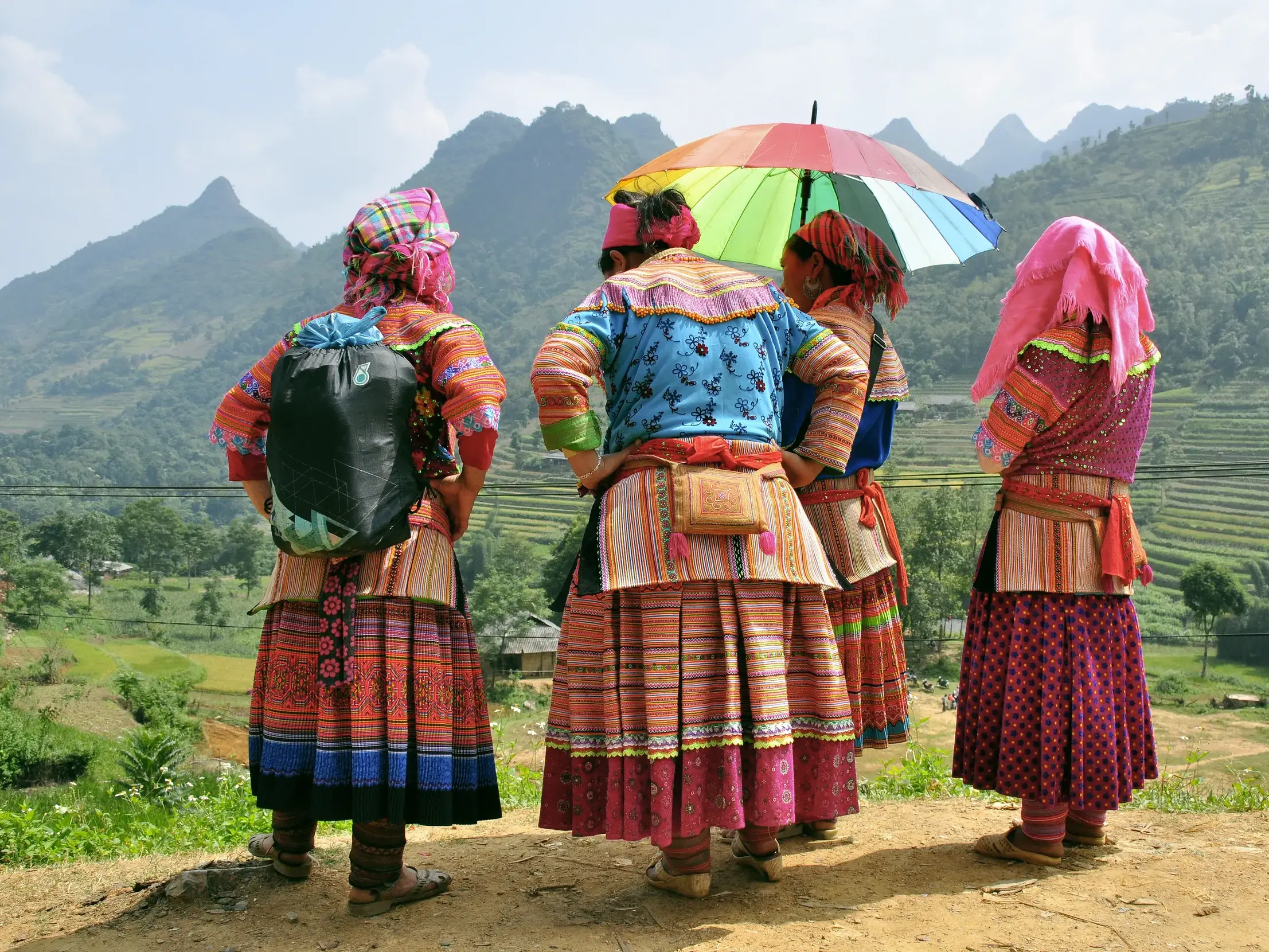 Rückansicht von vier Frauen eines Bergvolks in bunter Tracht während einer Wanderung in den Reisterrassen von Mai Chau.
