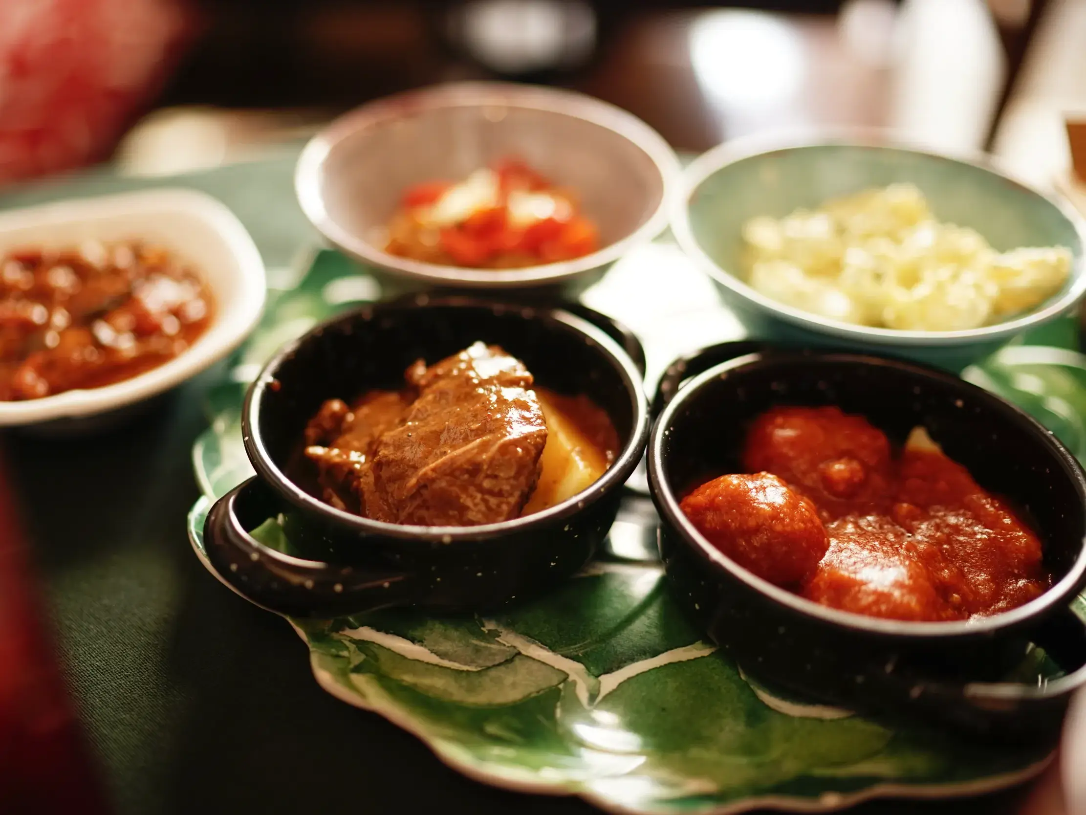 Vielfältige andalusische Tapas in kleinen Schalen, darunter Fleischeintopf und Albóndigas, als kulinarische Stärkung in Ronda.