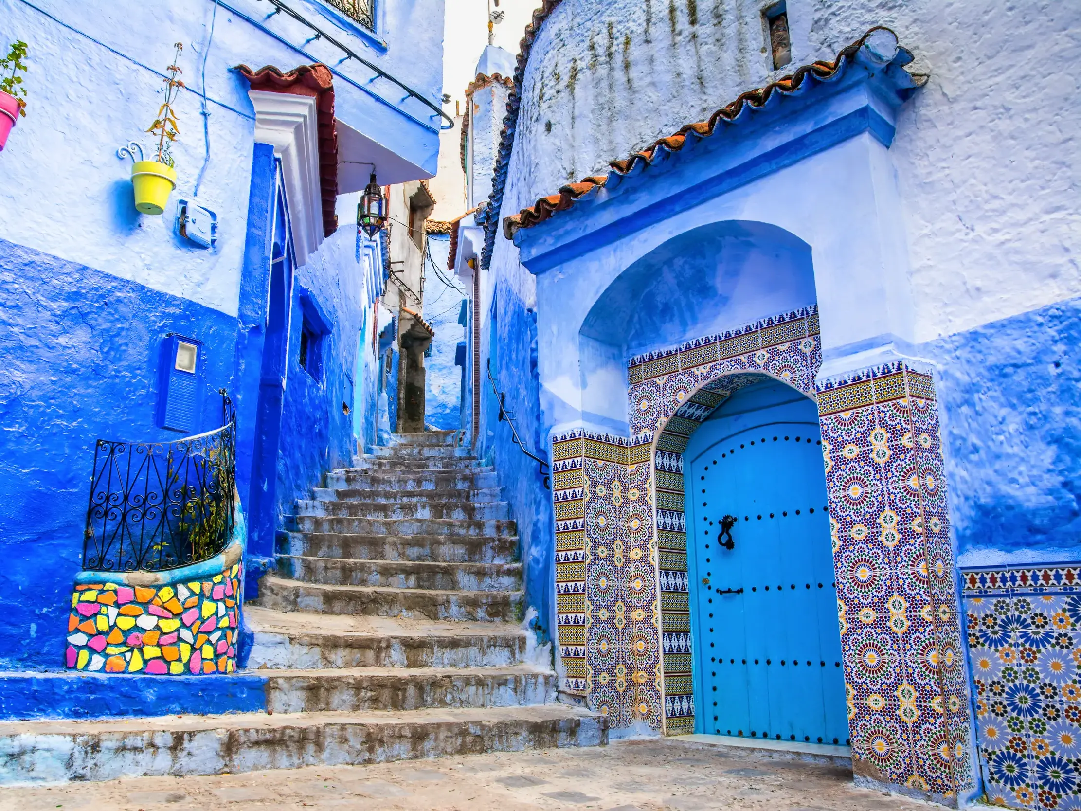 Malerische blaue Gasse mit Steintreppe und traditioneller Mosaiktür in der Medina von Chefchaouen