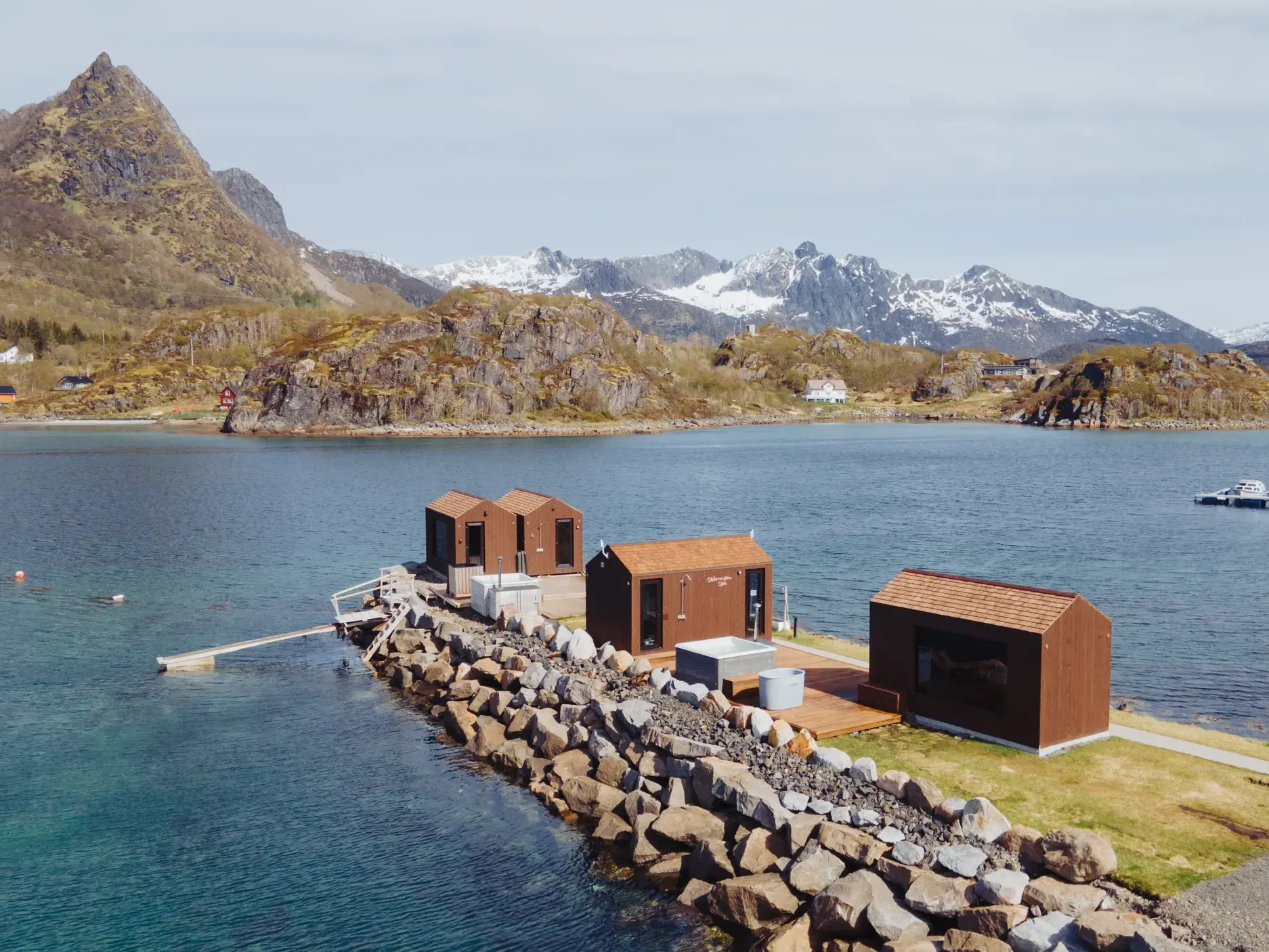 Private Holzhütten am Fjord auf den Lofoten mit Whirlpool, umgeben von der beeindruckenden Bergkulisse Norwegens.