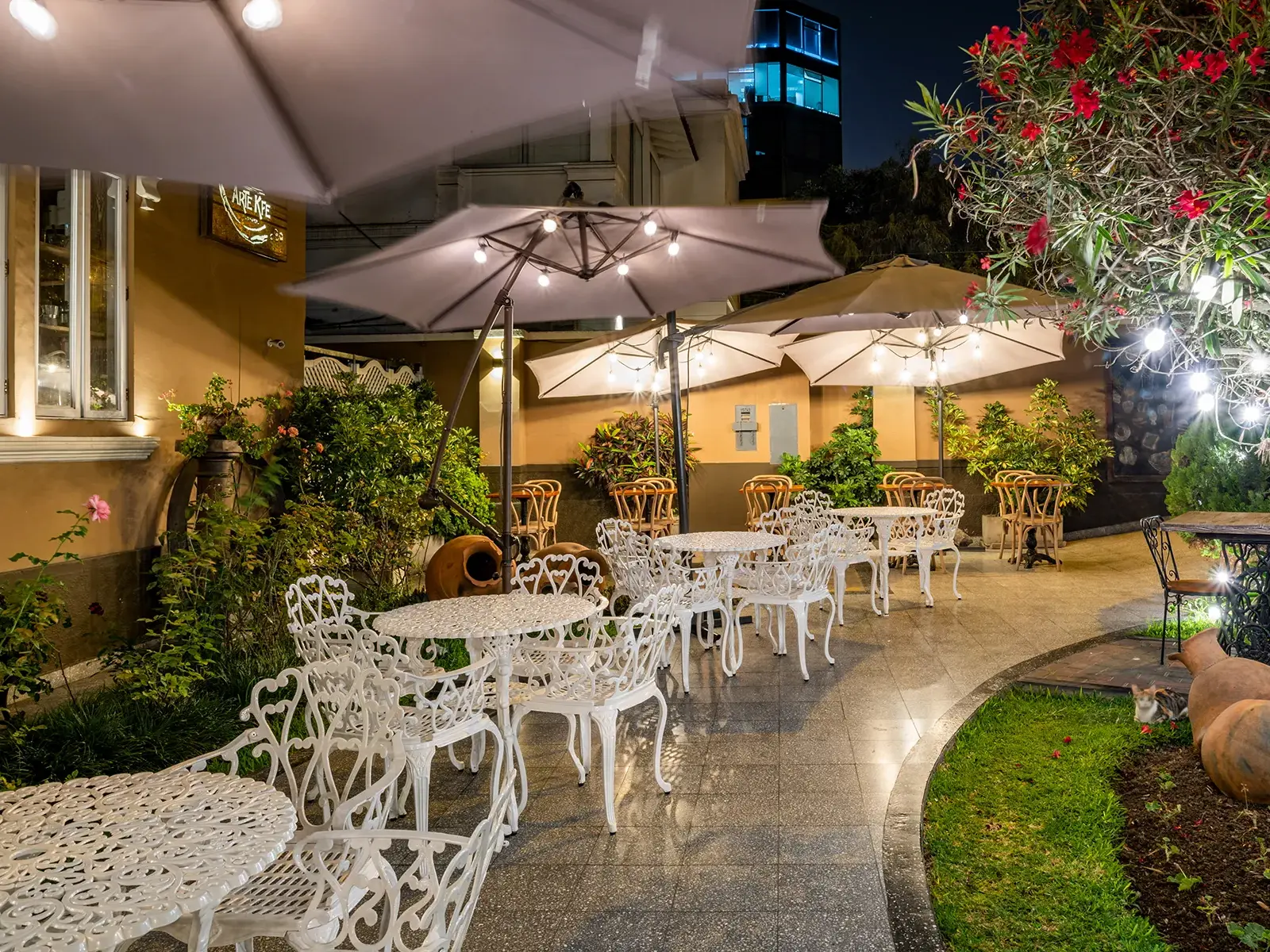 Der lauschige Innenhof des Hotel Antigua Miraflores in Lima bei Nacht, beleuchtet von Lichterketten über weißen Gartenmöbeln.