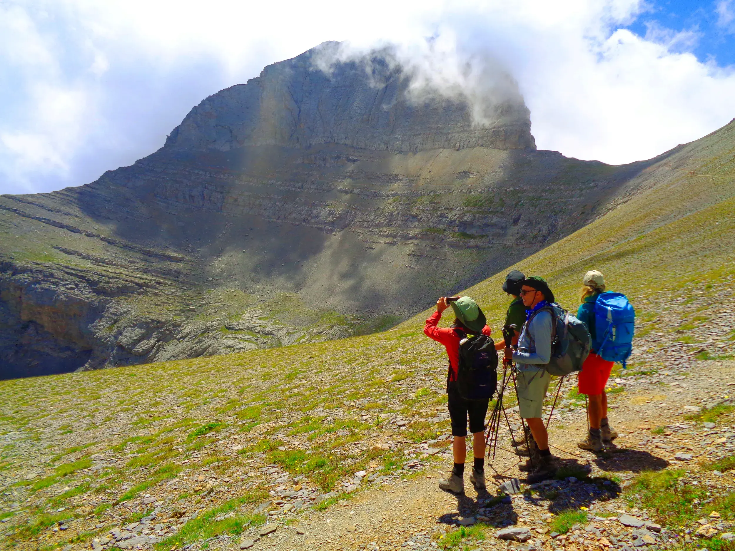 Eine kleine Trekking-Gruppe fotografiert während einer Pause den wolkenverhangenen Gipfel des Olymp-Massivs in Griechenland.