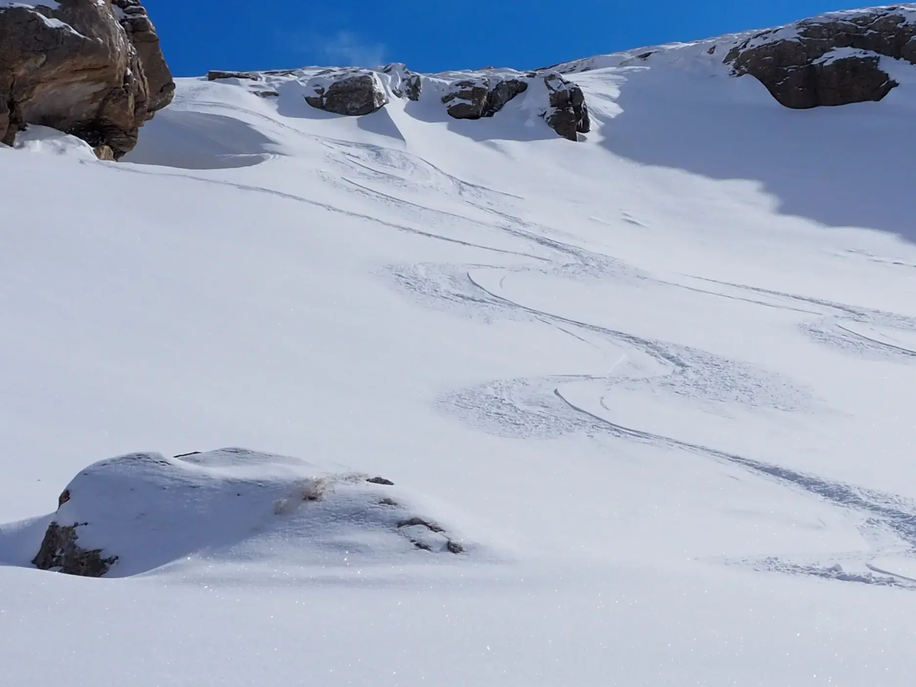 Frische Skispuren in einem weiten, unberührten Pulverschneehang im Sharr-Gebirge bei einer Skitour im Kosovo.