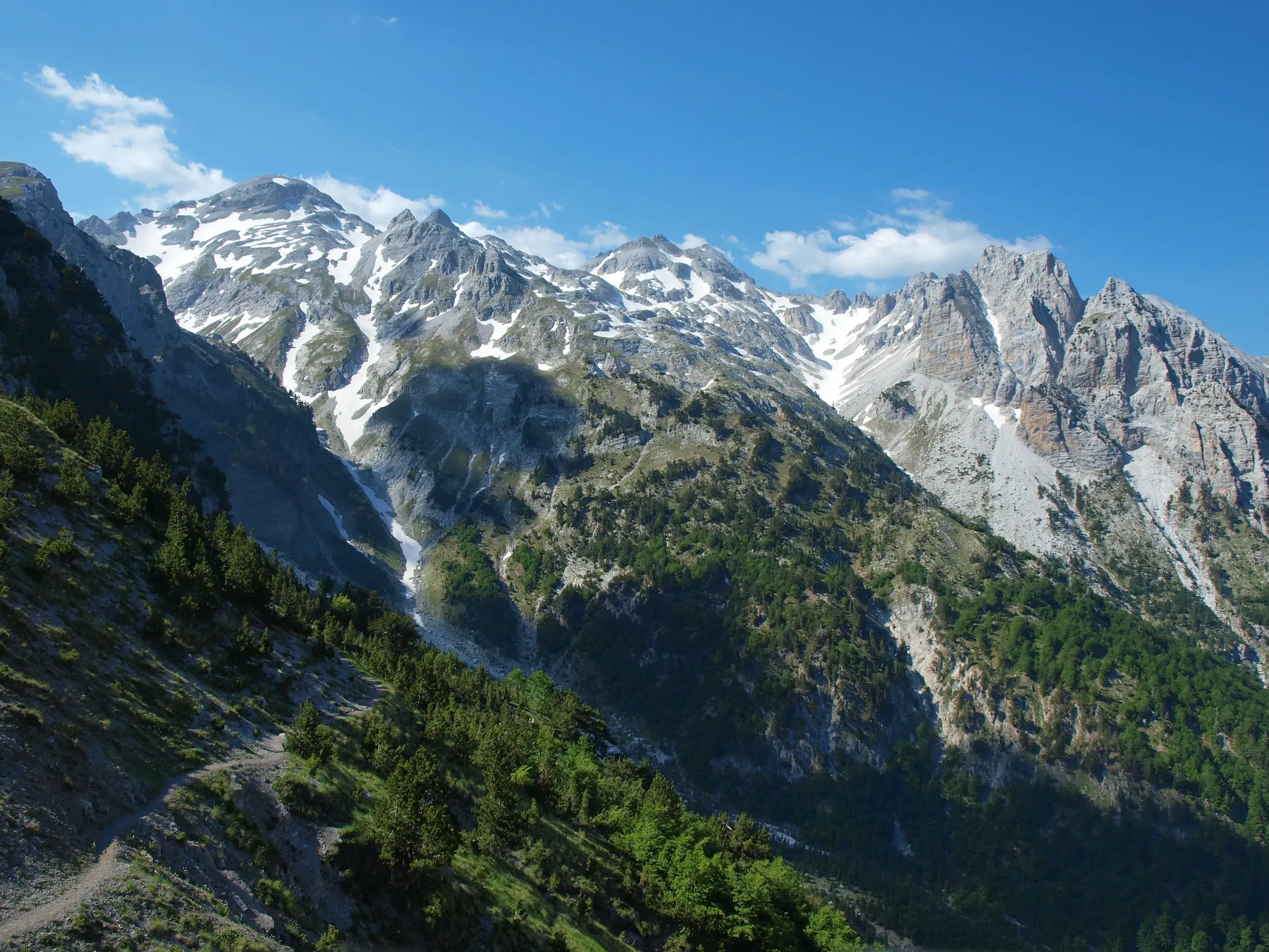Panoramablick auf die schroffen, schneebedeckten Gipfel der albanischen Alpen von einem Wanderweg am Valbona-Pass.