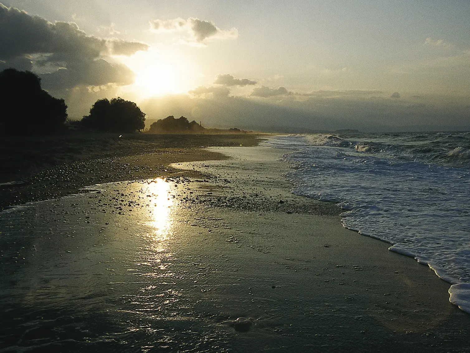 Goldener Sonnenuntergang am Kieselstrand auf Kreta, während die Wellen sanft auslaufen und sich das Licht im Wasser spiegelt.