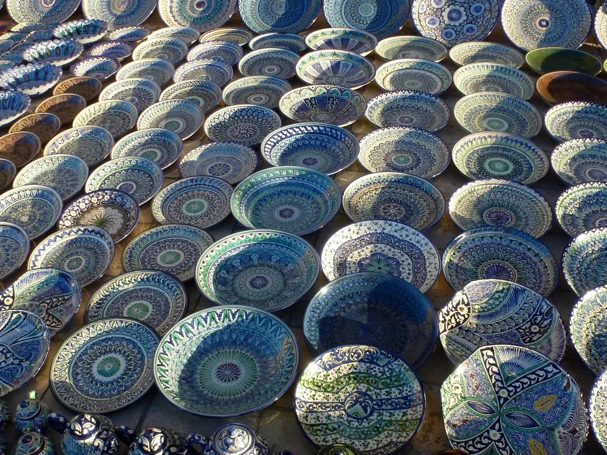 Farbenfrohe, handbemalte Keramik aus Usbekistan mit traditionellen Mustern auf einem Basar entlang der Seidenstraße.