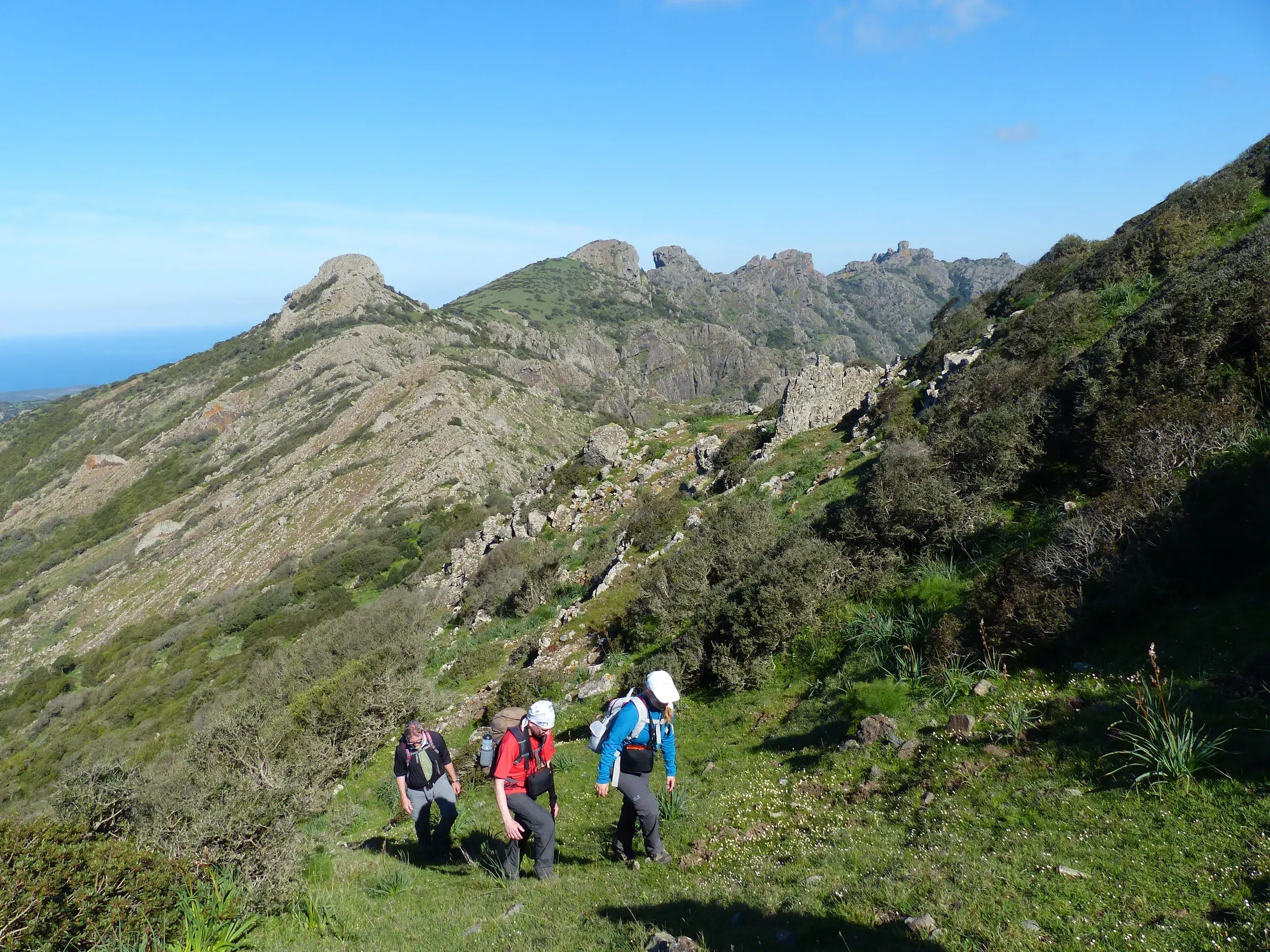 Eine Wandergruppe auf einem Trek in der bizarren Felslandschaft des Monte Arcuentu auf Sardinien mit weitem Blick auf das Meer.