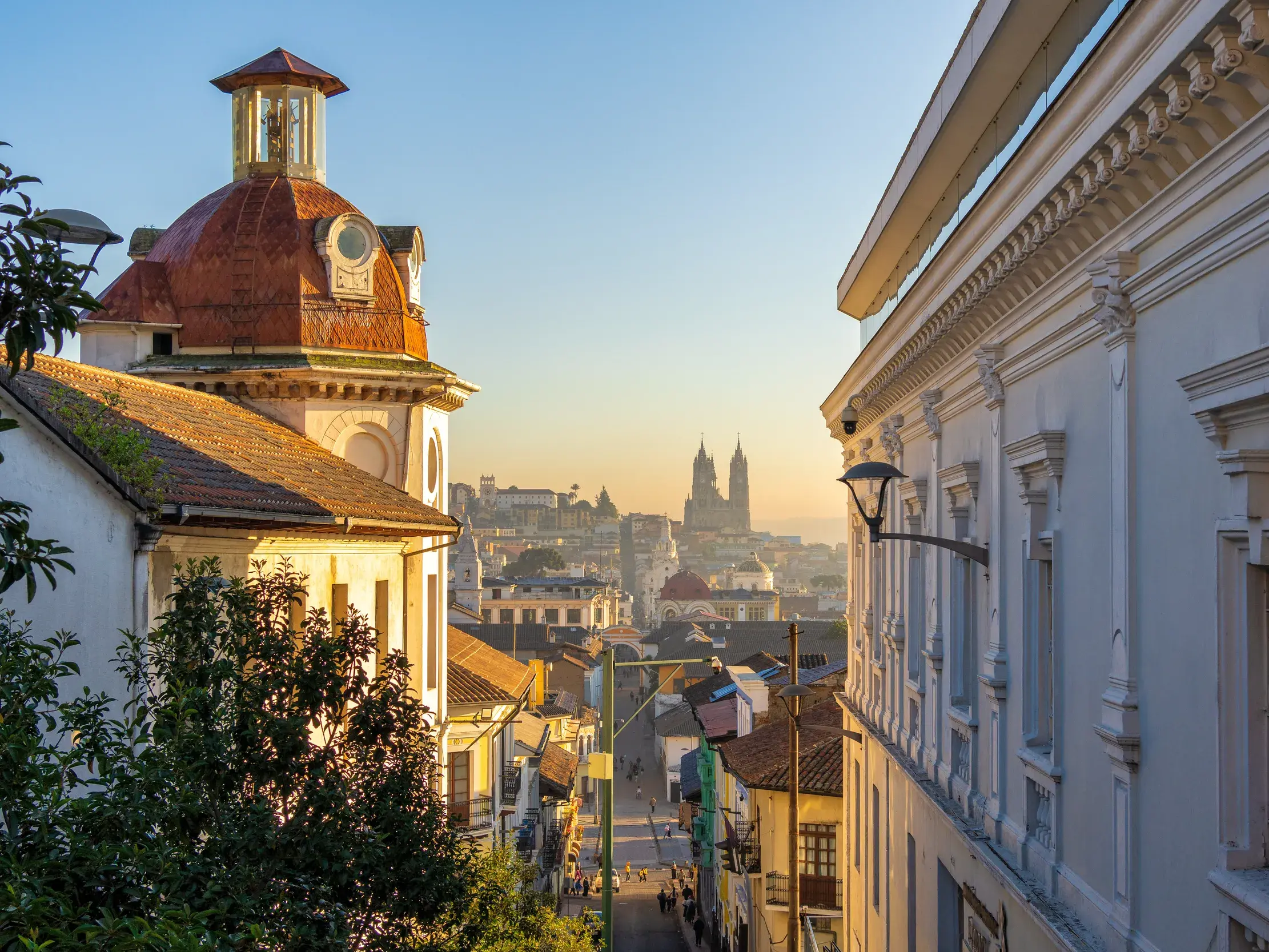 Gasse in der kolonialen Altstadt von Quito im warmen Morgenlicht, mit Blick auf die Türme der Basílica del Voto Nacional.