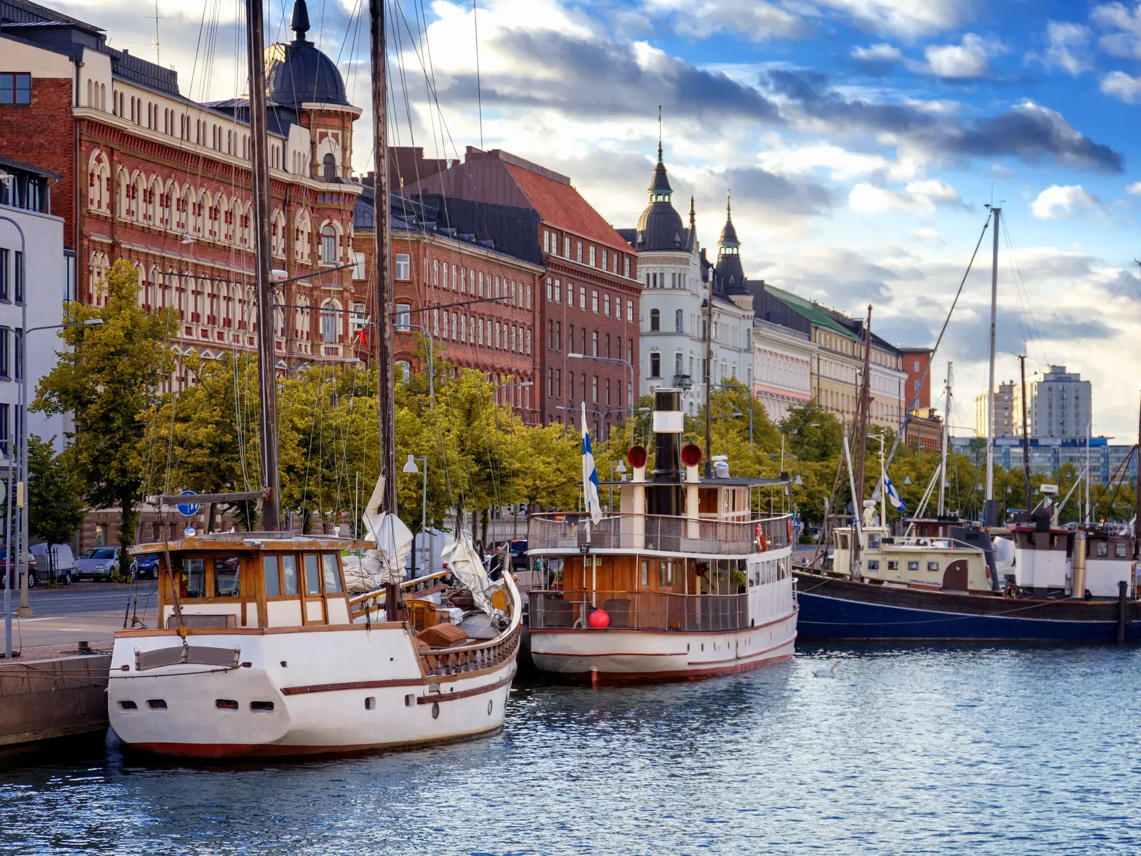 Traditionelle Boote und Segler liegen am Kai im Hafen von Helsinki vor der historischen Uferpromenade der Stadt.