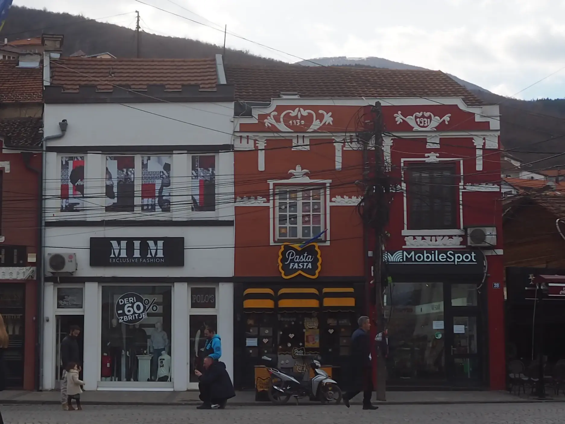 Straßenszene in der Kulturhauptstadt Prizren im Kosovo mit bunten, osmanisch geprägten Häusern und kleinen Geschäften.
