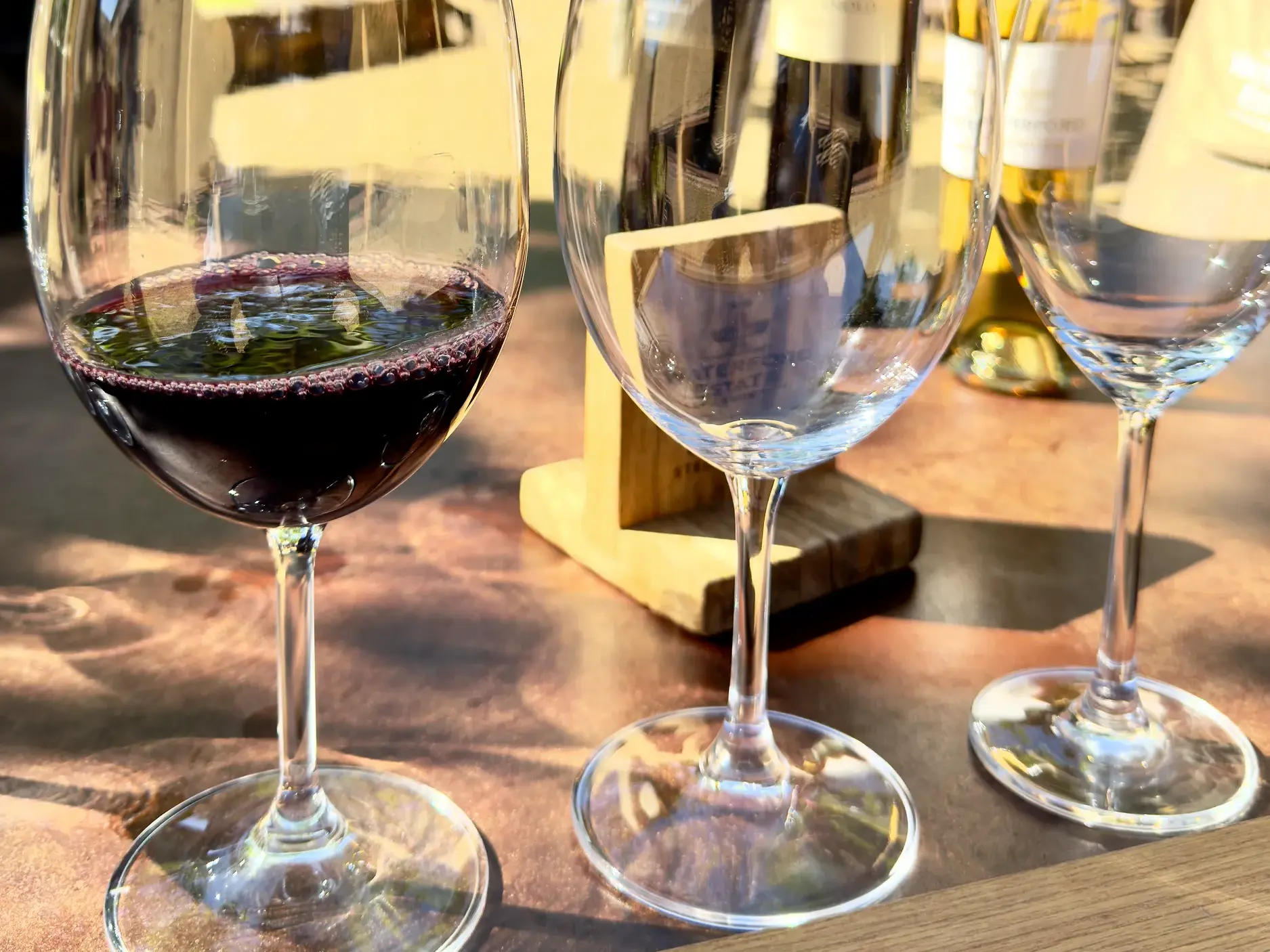 Ein Glas Rotwein neben leeren Weingläsern bei einer Weinprobe auf einer Kleingruppenreise in Stellenbosch, Südafrika.