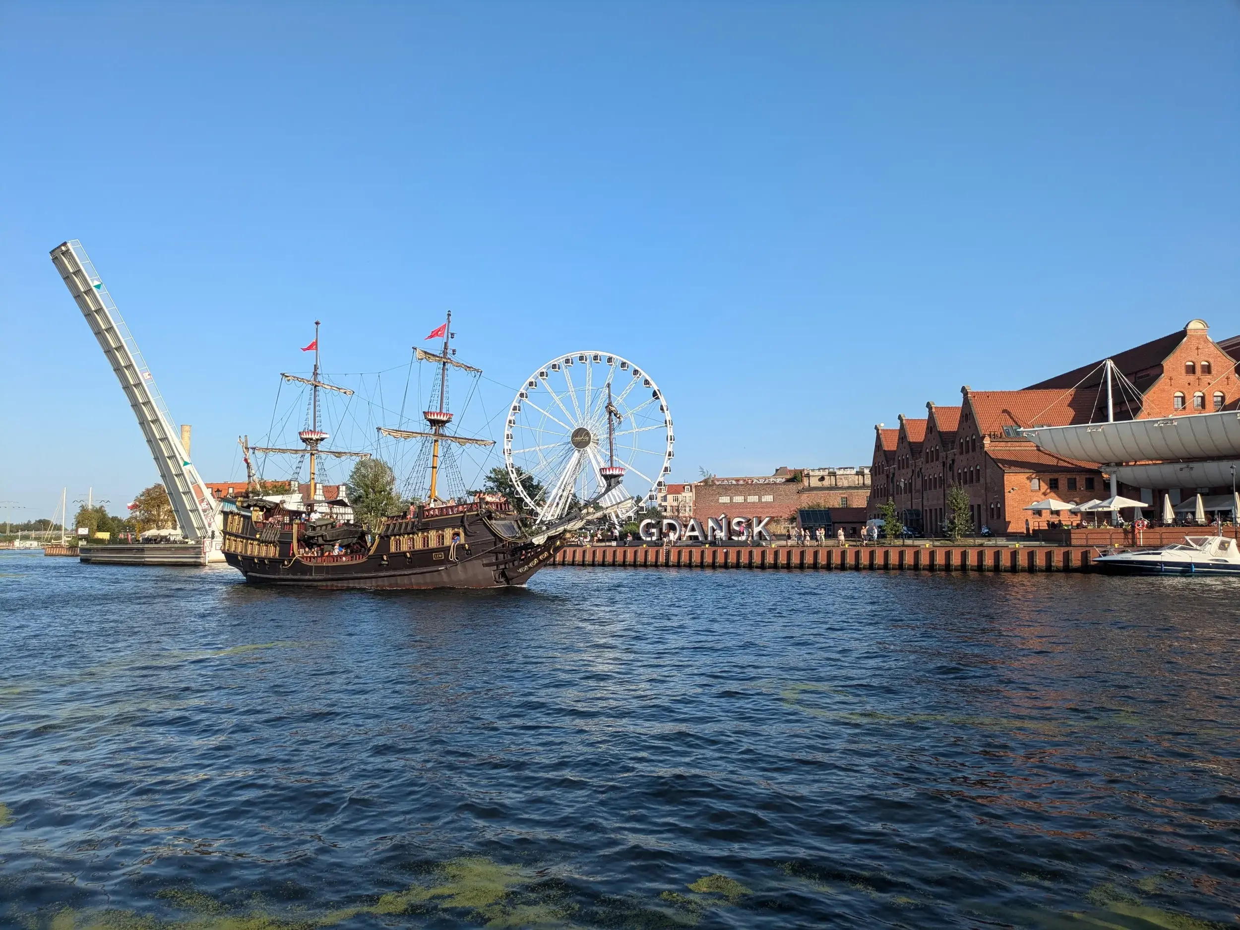 Historisches Ausflugsschiff auf der Mottlau im Zentrum von Danzig, vorbei am Riesenrad und den Backsteinhäusern der Hansestadt.