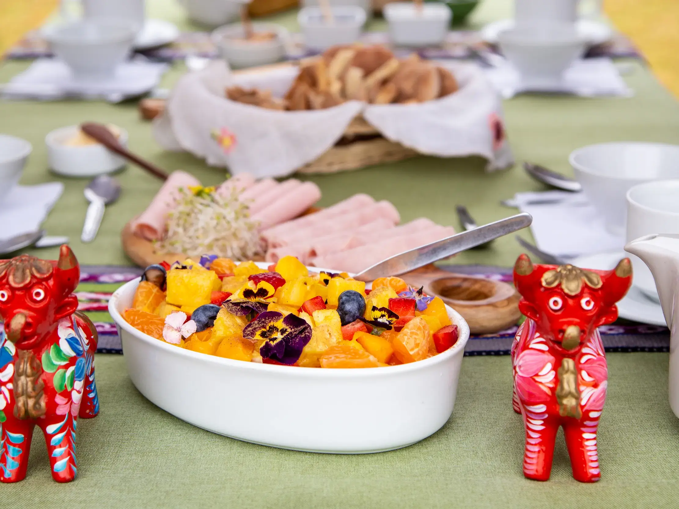 Reichhaltiges Frühstück während einer Wanderreise in den peruanischen Anden mit Obstsalat und traditionellen Keramikfiguren.