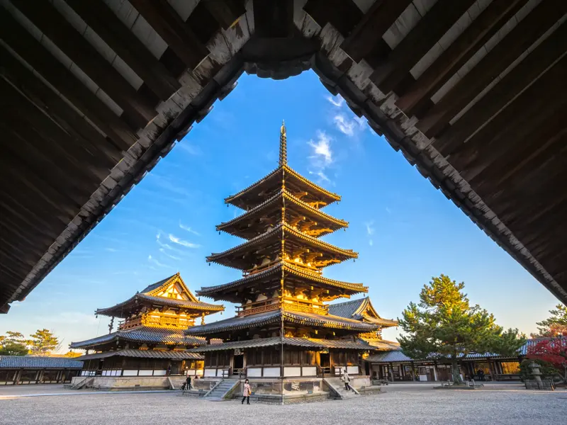 Fünfstöckige Pagode eines Tempelkomplexes in Nara im goldenen Abendlicht, gesehen unter einem traditionellen Vordach.