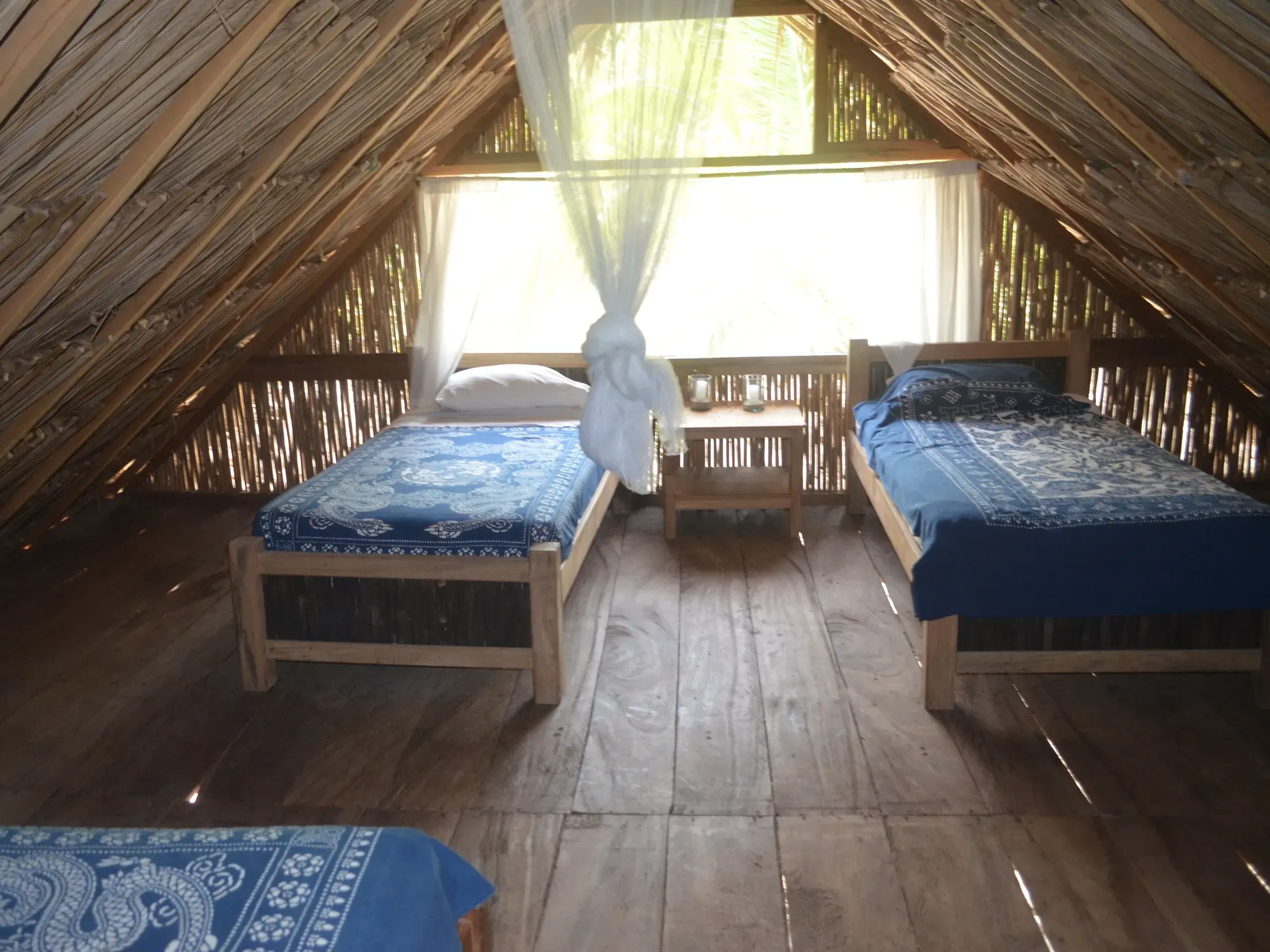 Rustikales Zimmer im Hotel El Matuy in Palomino mit drei Betten, Holzboden und strohgedecktem Dach an der Karibikküste.
