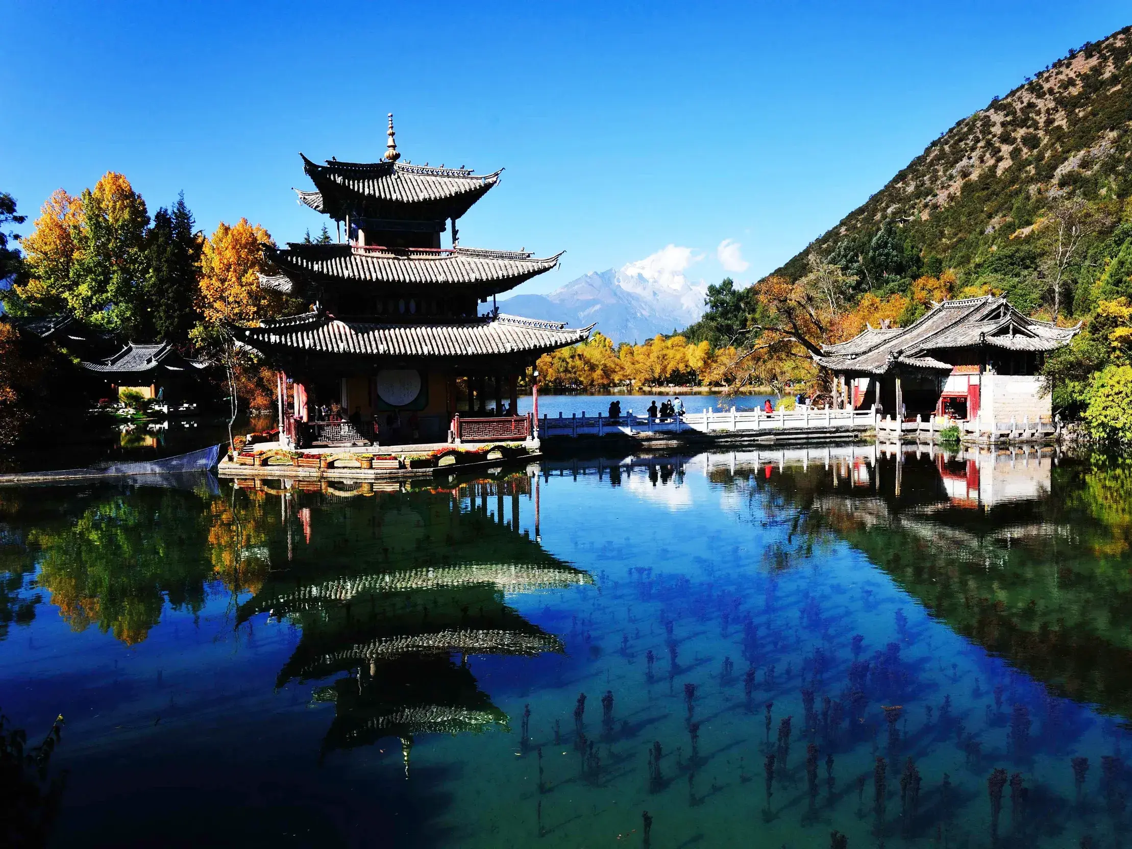 Traditionelle Pagode am klaren Schwarzen Drachen See in Lijiang, die sich vor dem Jade-Drachen-Schneeberg im Wasser spiegelt.