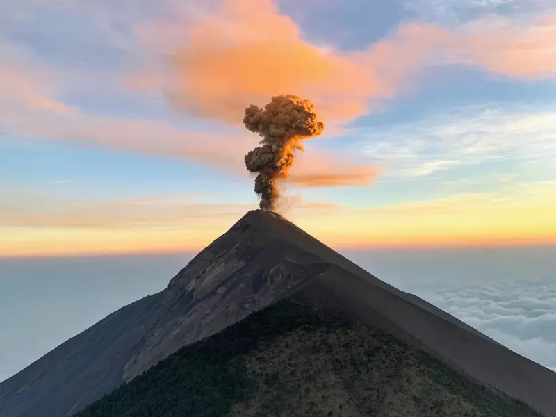 Eruption des Vulkans Fuego in Guatemala bei Sonnenuntergang, gesehen vom Gipfel des Acatenango über einem Wolkenmeer.