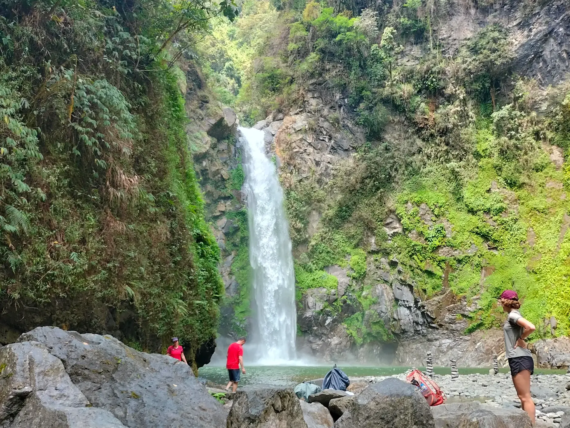 Eine kleine Wandergruppe macht eine Pause am beeindruckenden Tappiya-Wasserfall, der in einen natürlichen Pool in Luzon stürzt.