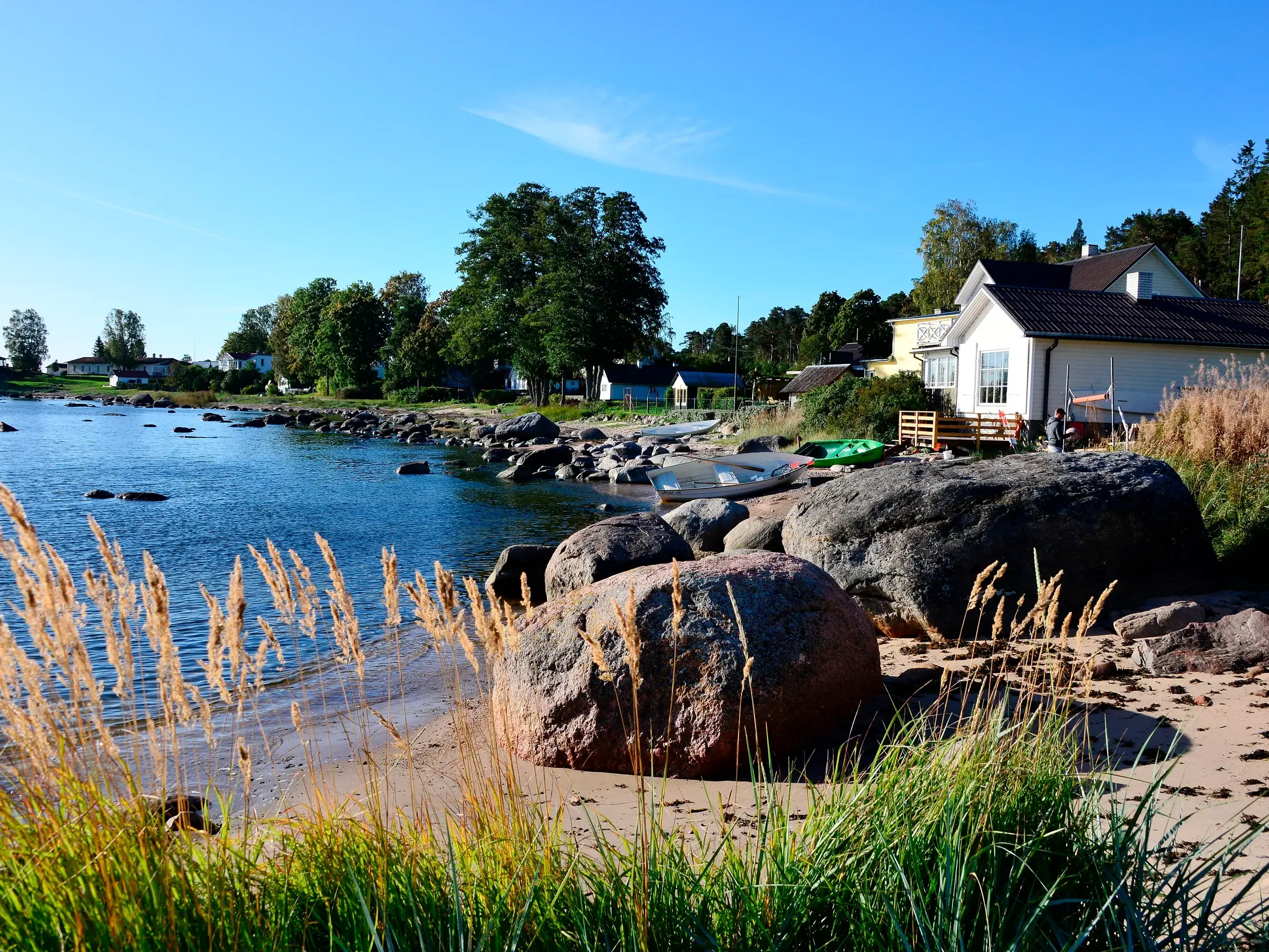 Studienreise Baltikum: Küste des Kapitänsdorfs Käsmu im Lahemaa-Nationalpark mit Findlingen am Strand und Holzhäusern.