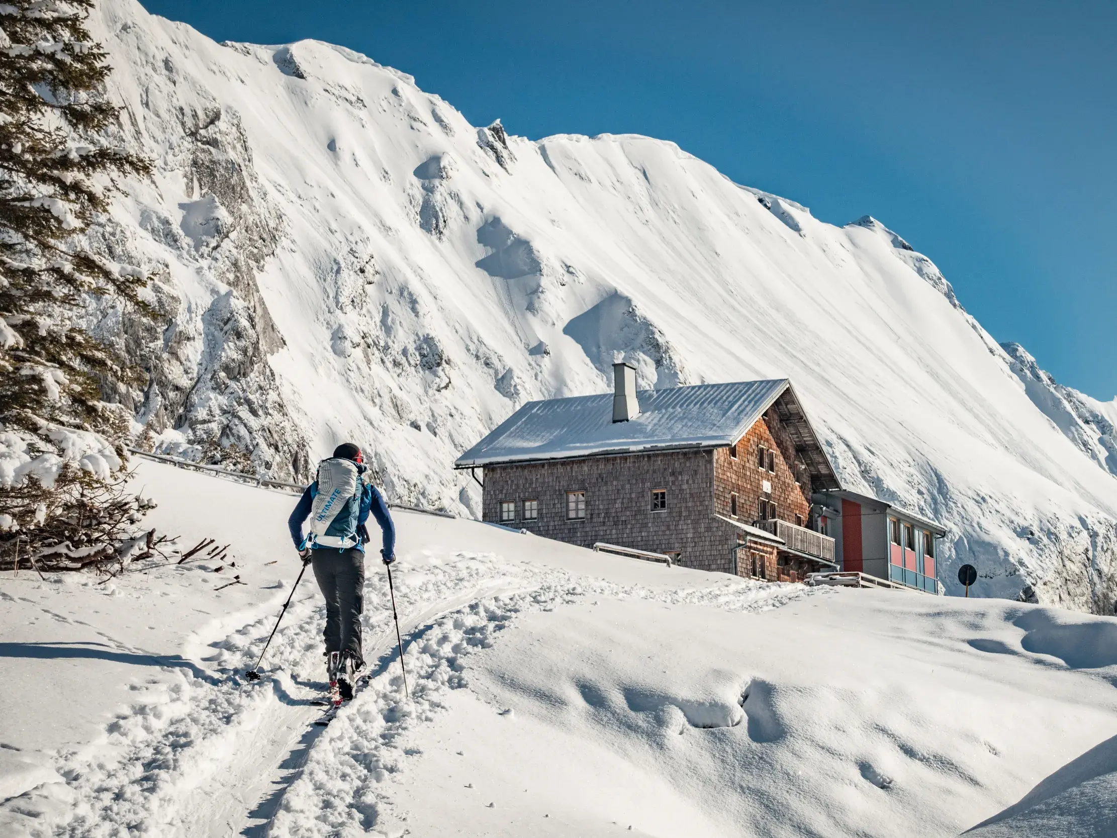 Ein Skitourengeher steigt durch eine tief verschneite Winterlandschaft auf zum Carl-von-Stahl-Haus in den Berchtesgadener Alpen.