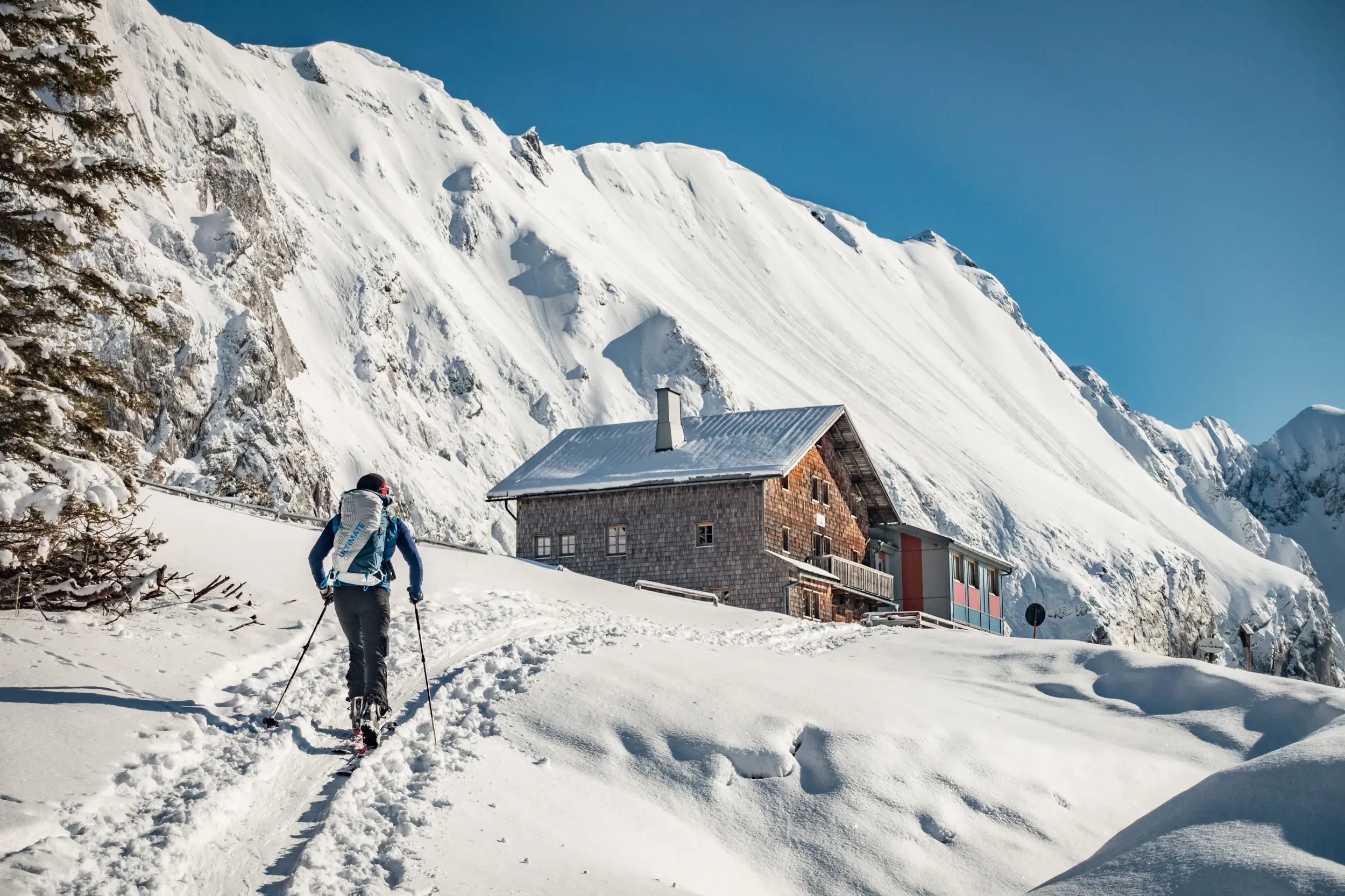 Ein Skitourengeher steigt durch eine tief verschneite Winterlandschaft auf zum Carl-von-Stahl-Haus in den Berchtesgadener Alpen.