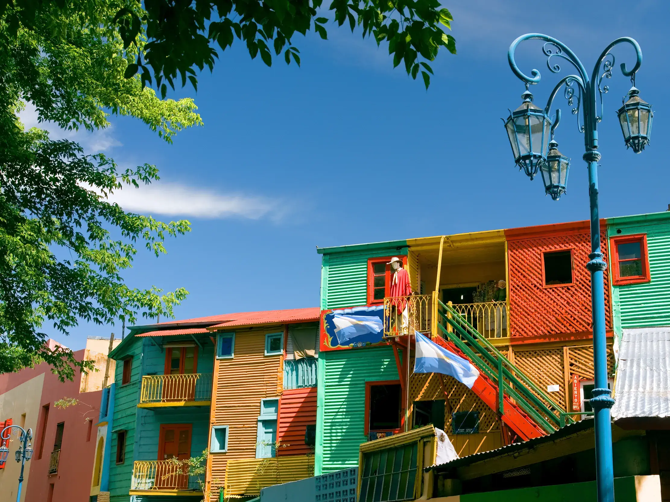 Bunte Wellblechhäuser mit Argentinien-Flaggen im berühmten Künstlerviertel La Boca in Buenos Aires an einem sonnigen Tag.