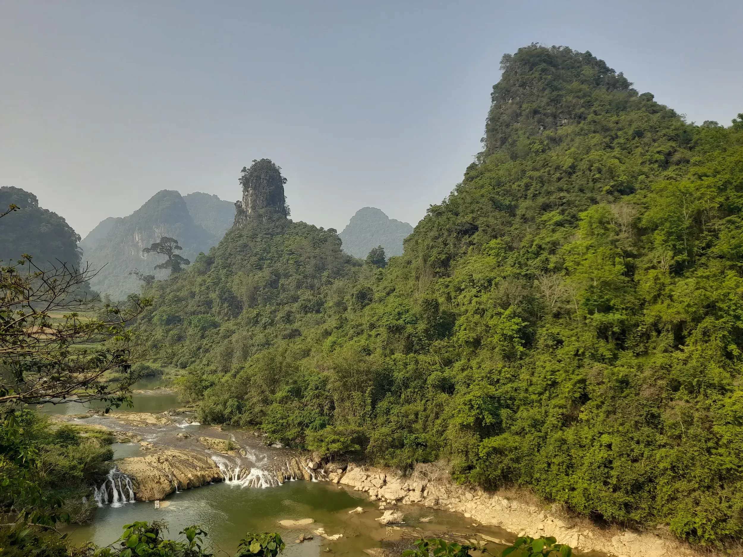 Der Fluss Bac Vong mit seinen Kaskaden fließt durch die grüne Dschungellandschaft mit Karstbergen bei Cao Bang in Vietnam.
