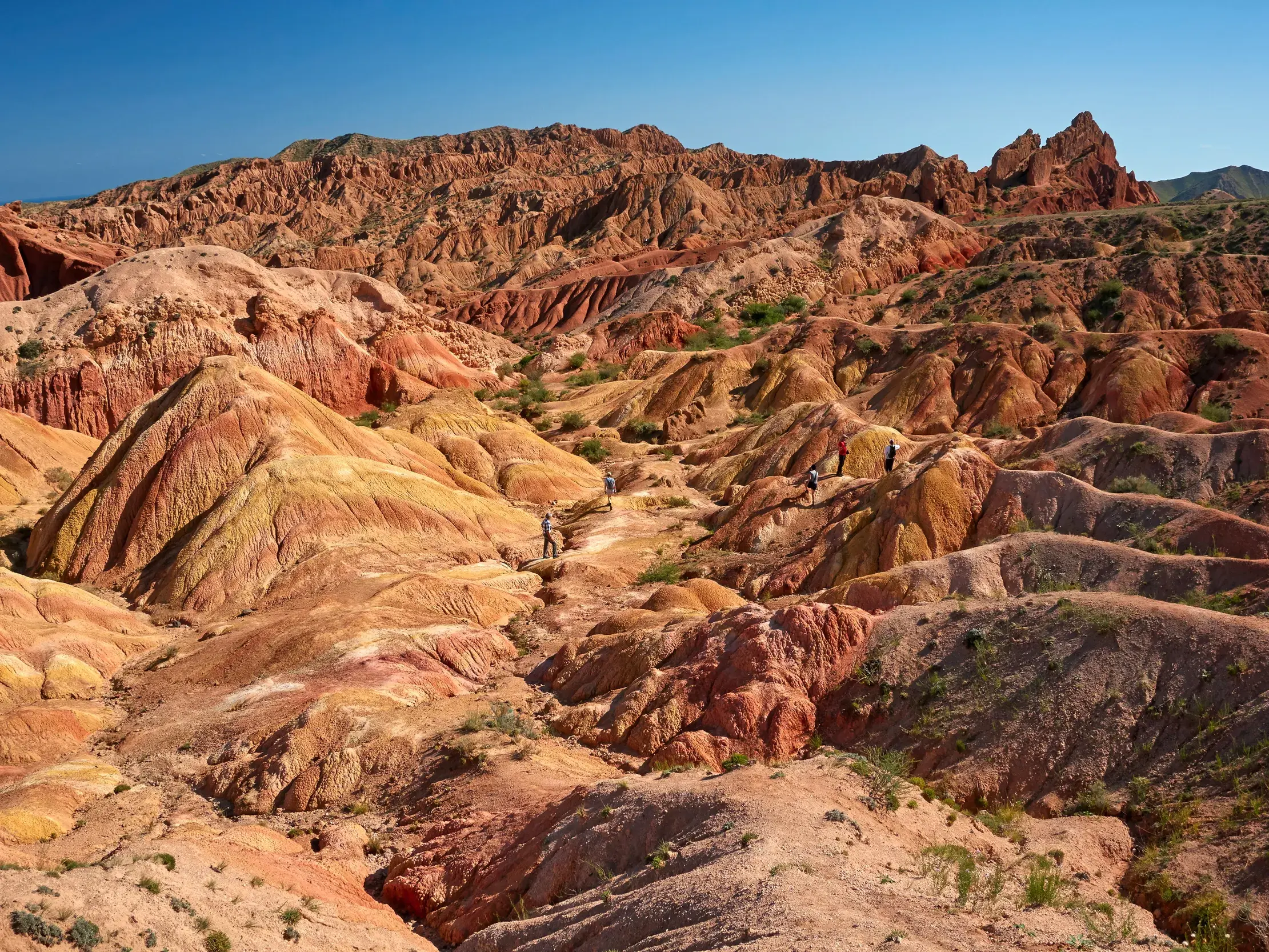 Eine Reisegruppe wandert durch die bizarren, roten Felsformationen des märchenhaften Skazka Canyon in Kirgistan.