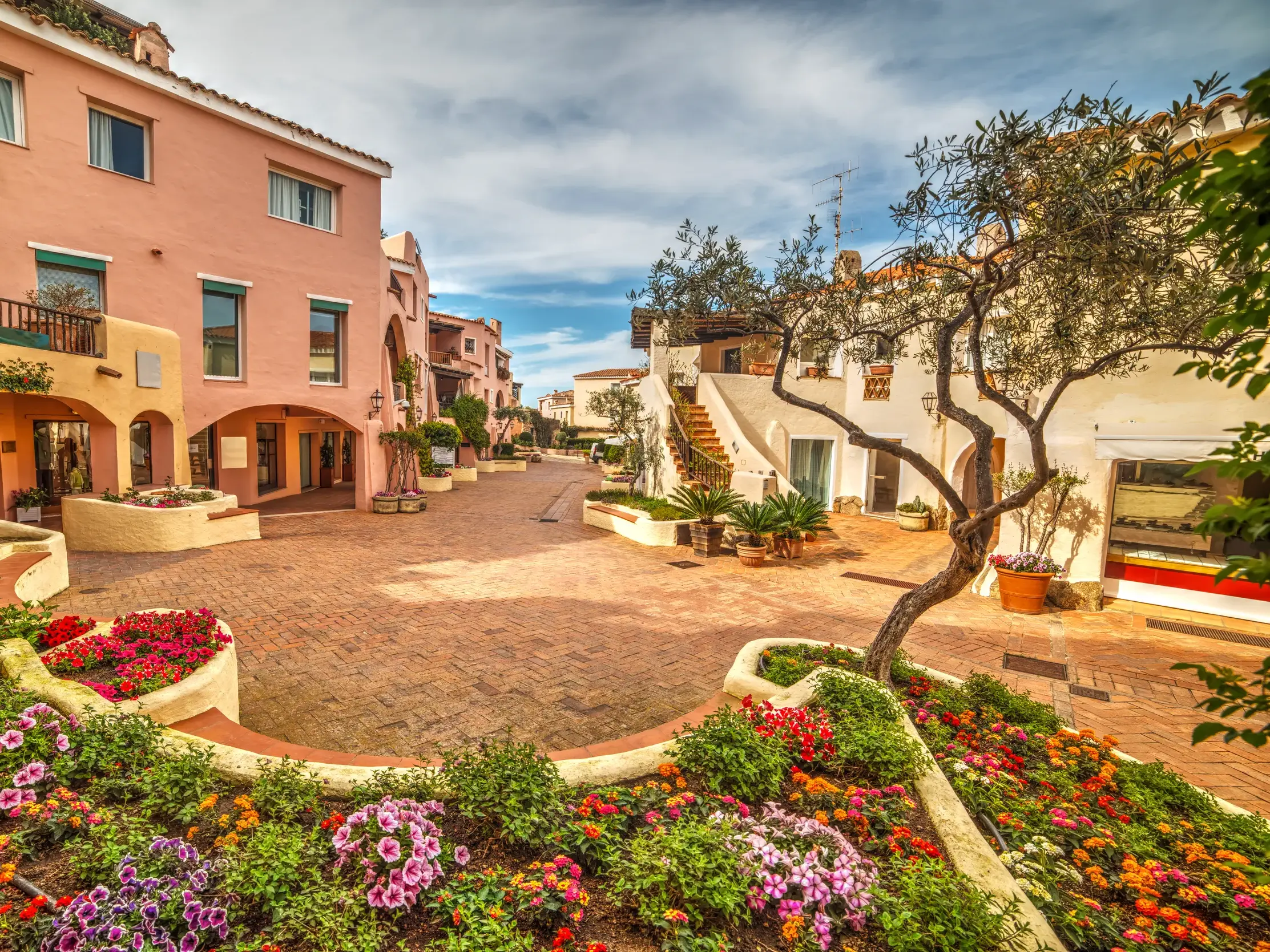 Malerische Gasse in Porto Cervo an der Costa Smeralda mit farbenfrohen Blumenbeeten und mediterraner Architektur.