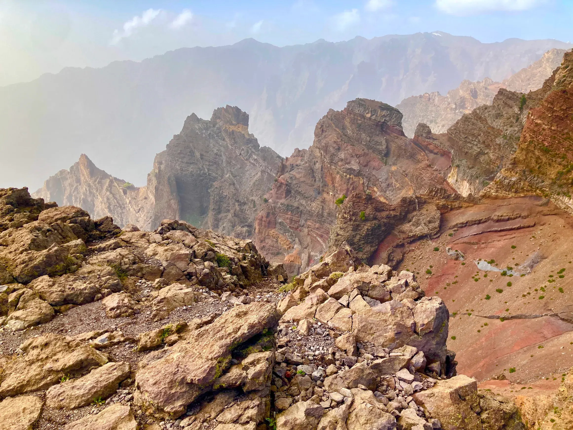 Ein schmaler Wanderweg führt durch eine karge, felsige Vulkanlandschaft mit Blick in die Caldera de Taburiente auf La Palma.